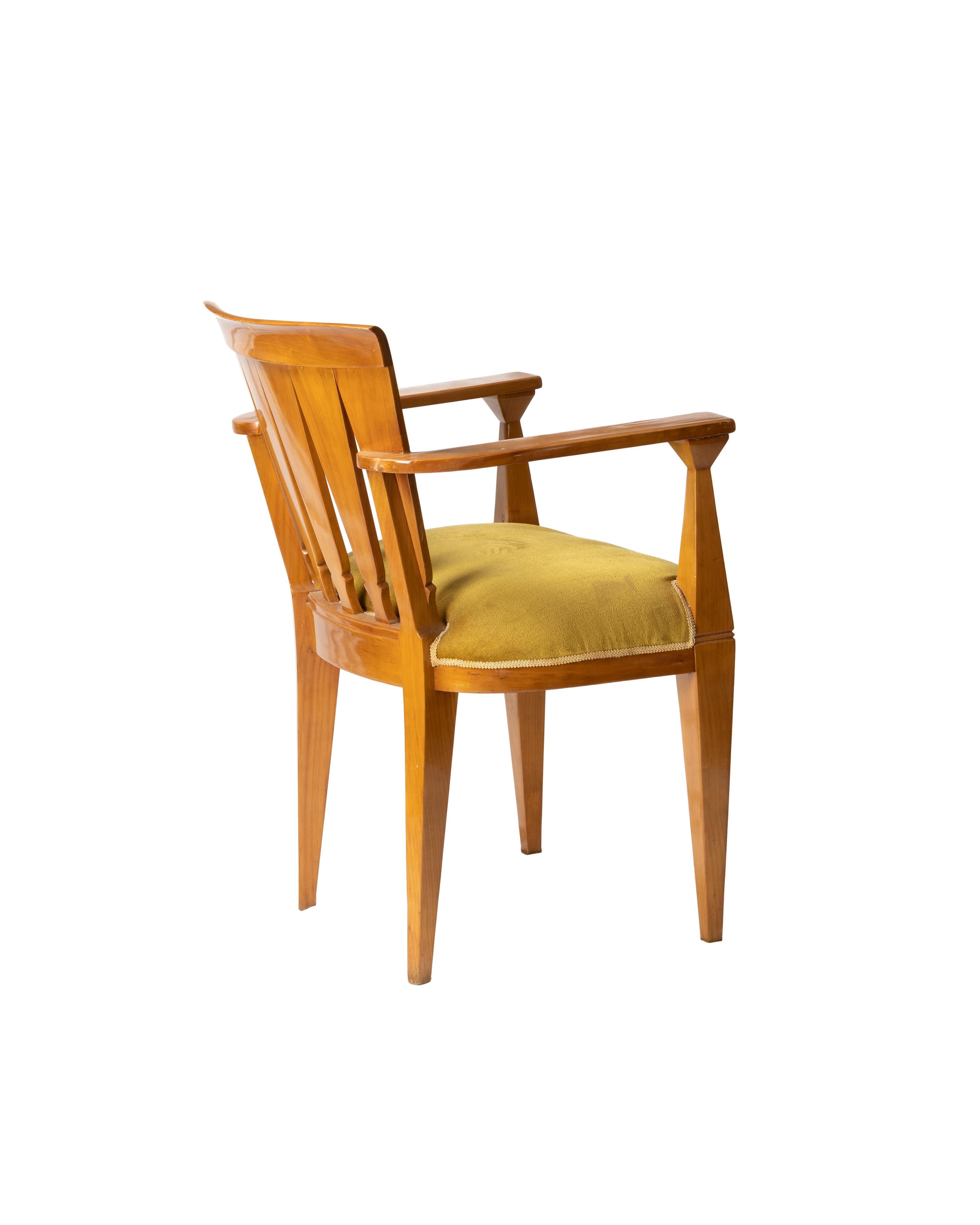 This Art Deco armchair showcases the sleek geometry and craftsmanship typical of the early 20th century French design. The curved, fan-like scalloped backrest is carved with striking triangular slats, paired with angular armrests and tapered