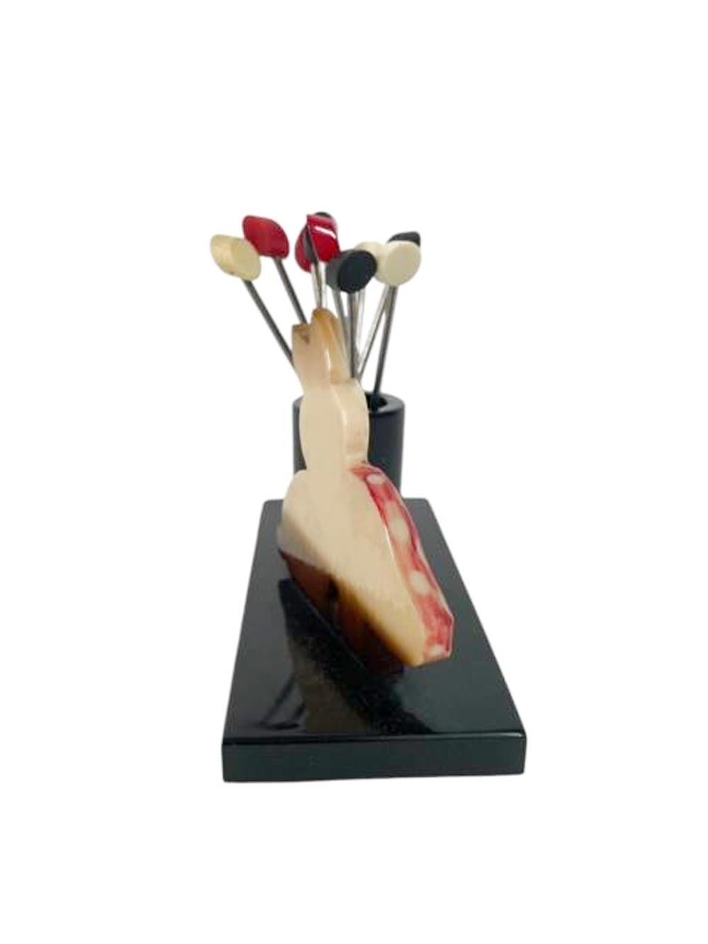 Art Deco Bakelite cocktail pick set - a rabbit standing next to a toadstool by a Bakelite cylinder holding 9 cocktail picks topped with diagonally cut disks of black, white and red Bakelite, all on a rectangular black Bakelite base.