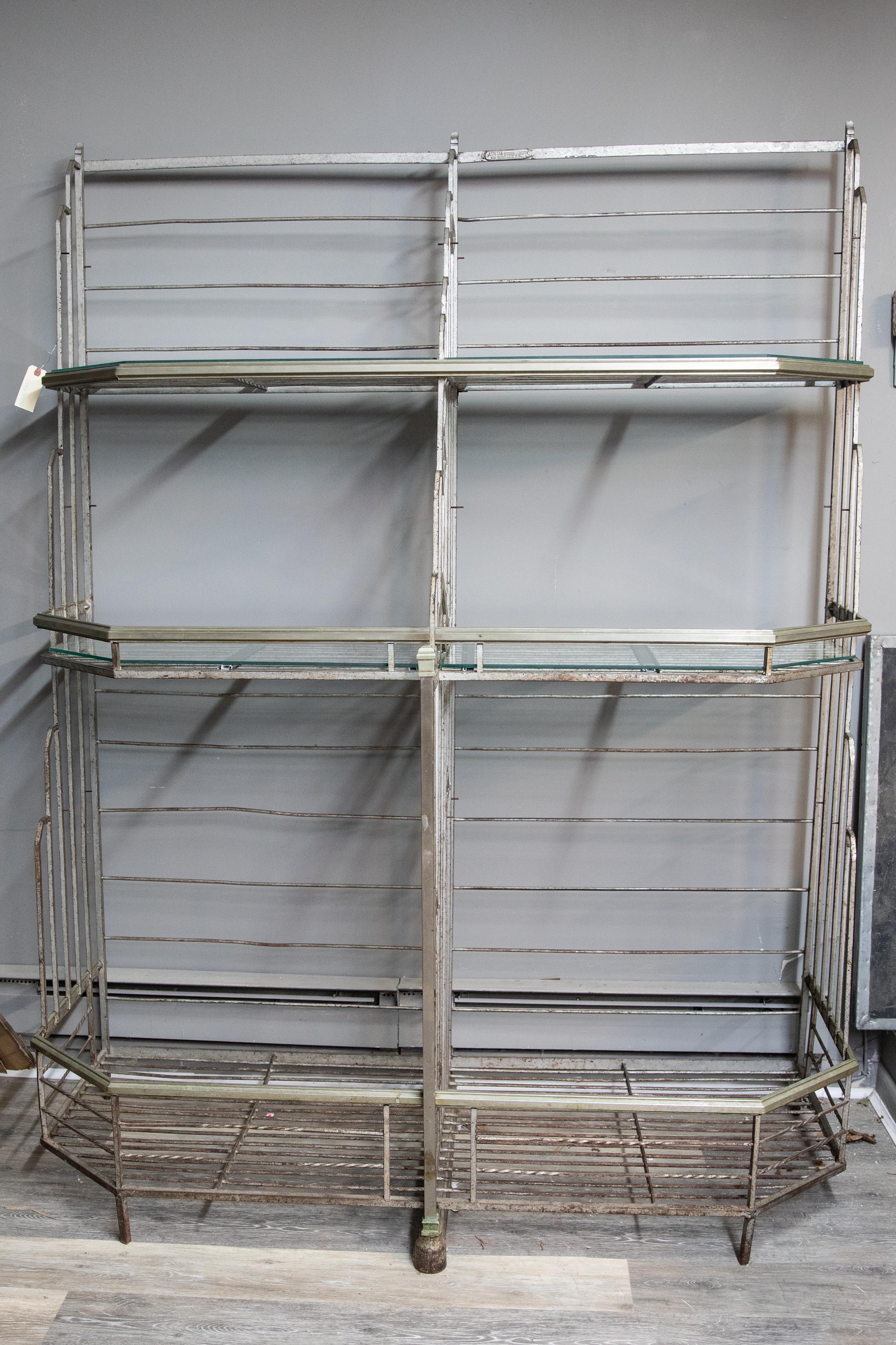 This is a stunning French Art Deco bakers rack marked Lyon, France. It has been fitted with glass shelves except for the bottom two. It is a sculptural and geometric beauty that combines form and function. This iron rack has a large open gallery at
