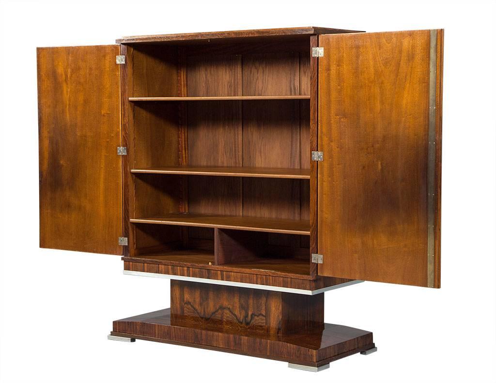 This Art Deco style bar cabinet hails from France. A vintage piece composed of solid wood, the doors are finished in a book matched patterned grain and a gorgeous brown stain. In excellent condition, this cabinet is a perfect fit for a rustic home.