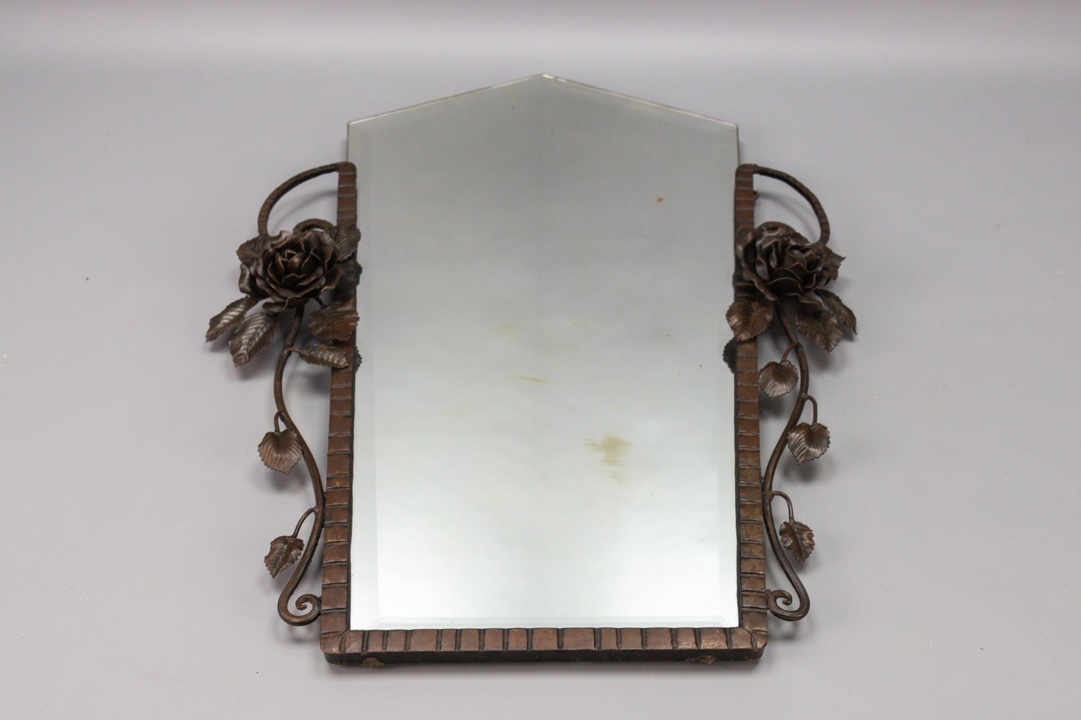 French Art Deco beveled wall mirror with wrought iron frame, decorated with beautiful roses, rose leaves, and scrolls, circa the 1930s.
The fixing chain is present on the backside.
In good and age-appropriate condition. The mirror has signs of aging