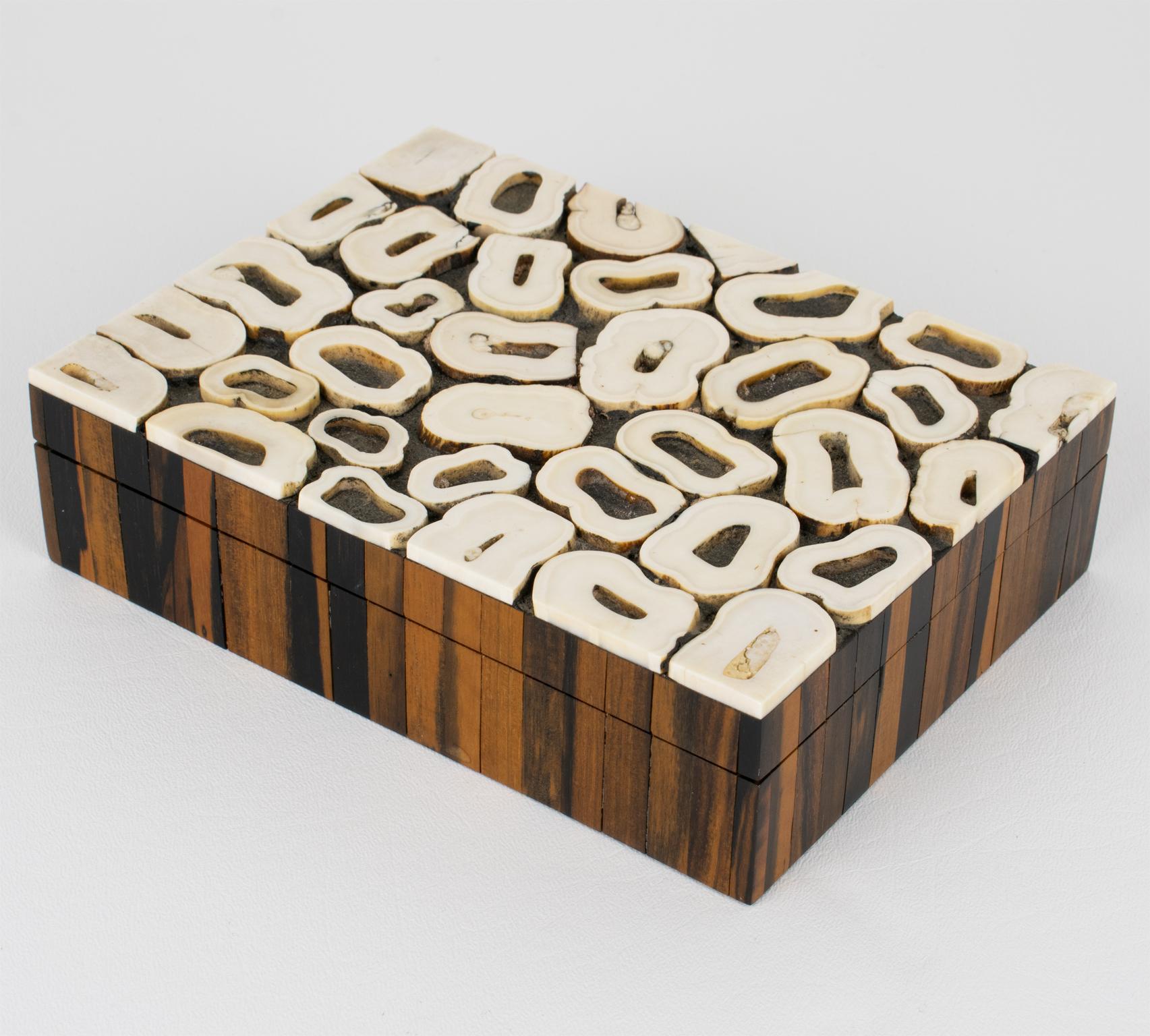 Esta elegante caja Art-Deco con tapa se fabricó a mano en Francia en la década de 1930. La parte superior de la tapa está adornada con marquetería de hueso. El diseño es muy modernista y utiliza rodajas de huesos de vacuno para formar una decoración