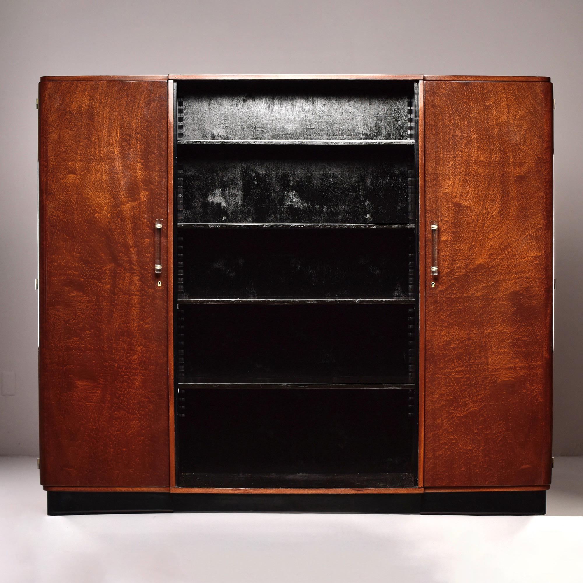 Circa 1940s French bookcase cabinet features center section of four open, adjustable shelves flanked by side cabinets that each have four adjustable shelves. Cabinetry has a veneer of and African wood called Sapele Mahogany or Pomelle Sapele. Lucite