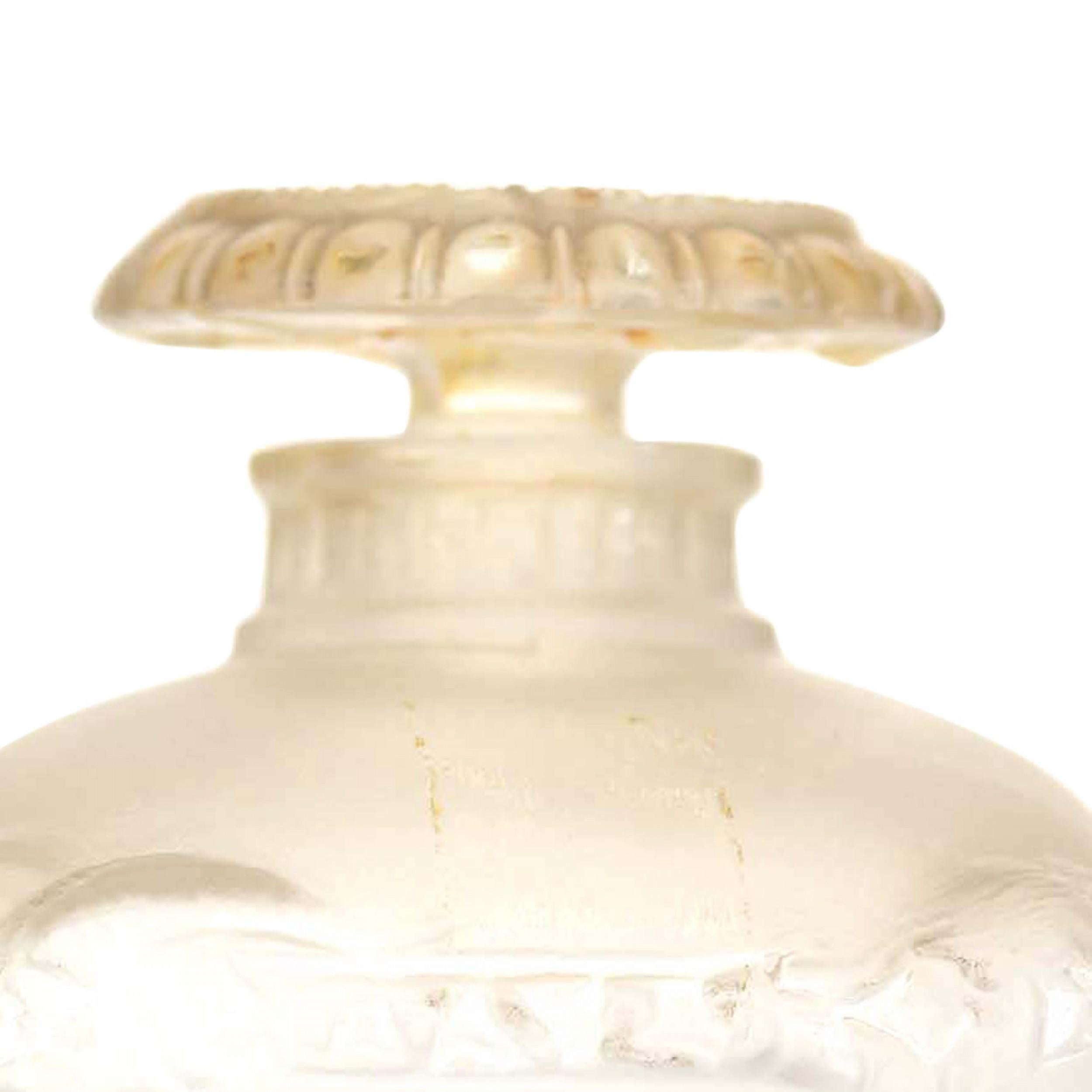 Bottiglia di profumo in vetro smerigliato a forma di urna con piede (BOUQET DE FAUNES di GUERLAIN), con quattro teste di fauni mitici in alto rilievo intorno al corpo e un tappo appiattito con un disegno di perline in rilievo, un bordo smerlato e