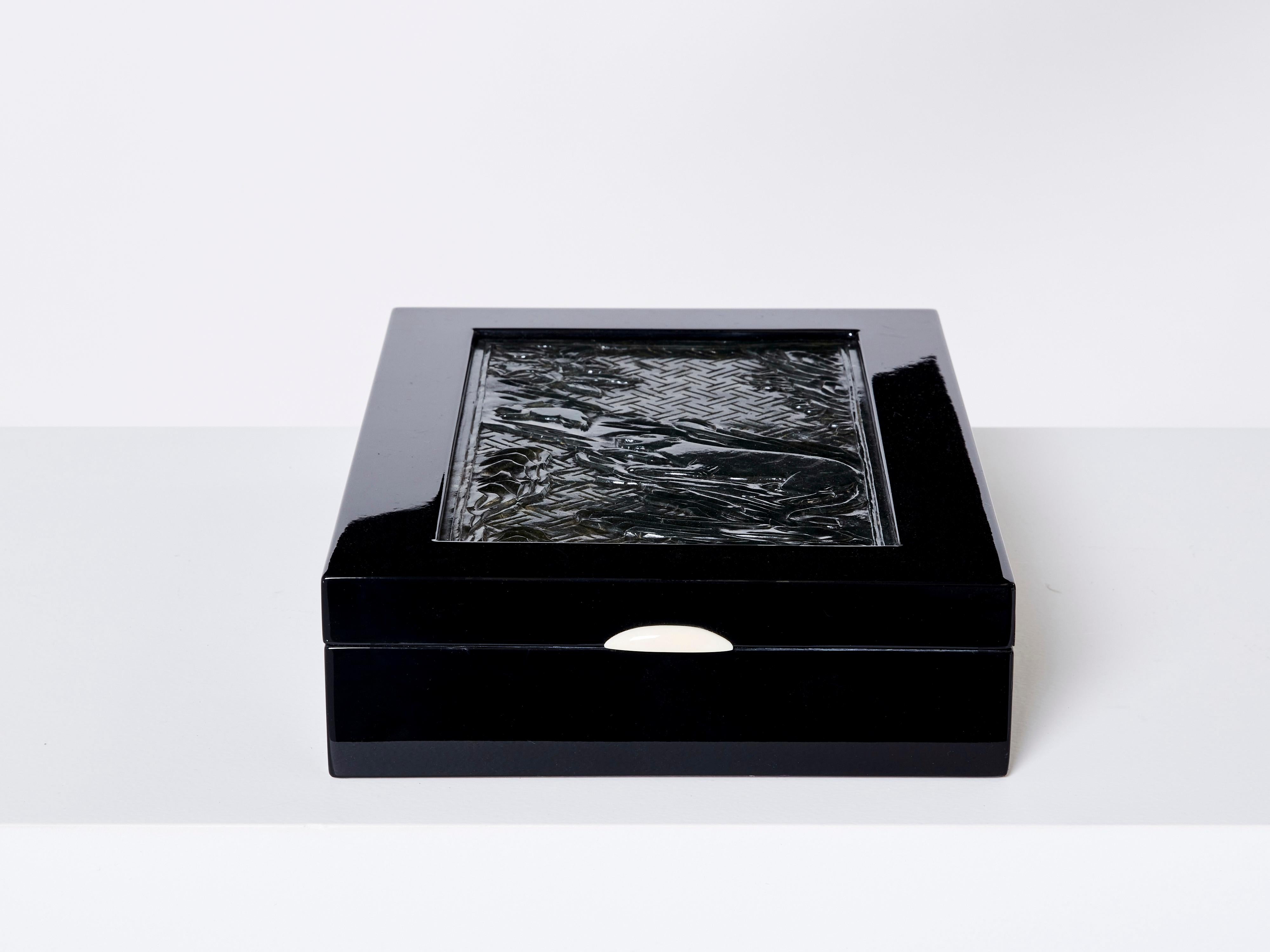 Boîte à bijoux Art déco française unique des années 1930. Cette boîte en bois laqué noir présente sur son couvercle une pierre de jade vert foncé magnifiquement sculptée, représentant une scène avec une panthère poursuivant un lapin. Il a été
