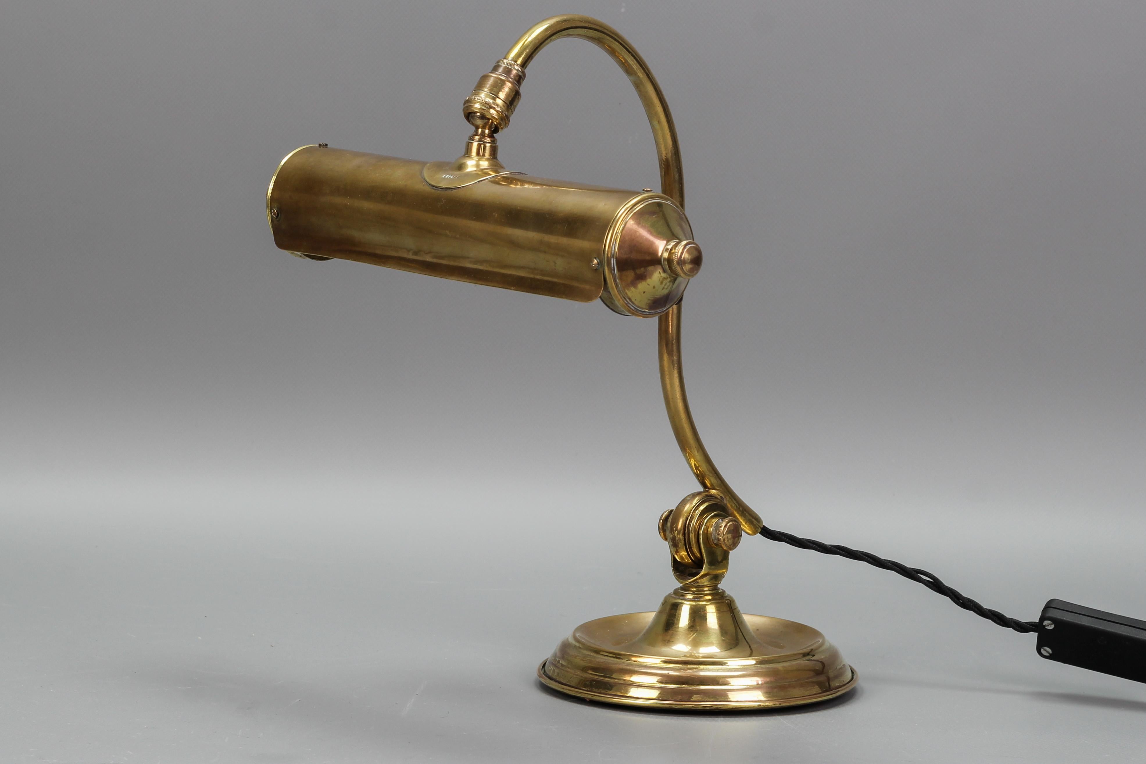 French brass Adjustable Desk Lamp, circa the 1930s
The beautiful cylindrical shaped shade of the banker's or piano Art Deco desk lamp is mounted on an adjustable swan neck support arm, attached to a circular weighted brass and metal base.
One new