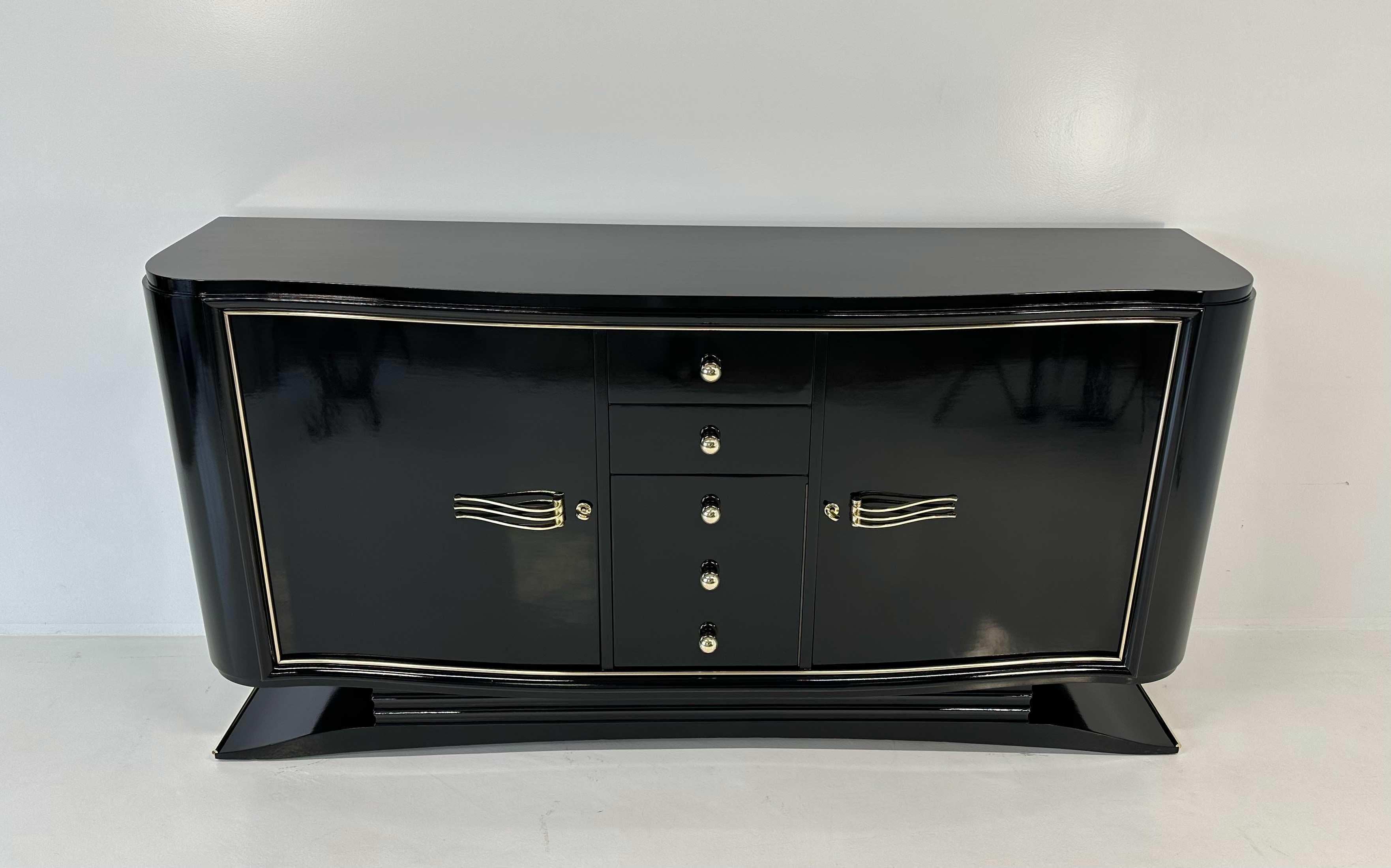 Splendida credenza francese risalente alla metà del XX secolo, caratterizzata da un raffinato design modernista. Laccato interamente in un nero profondo e lucido, questo pezzo si distingue per le eleganti finiture in ottone, che ne esaltano le linee