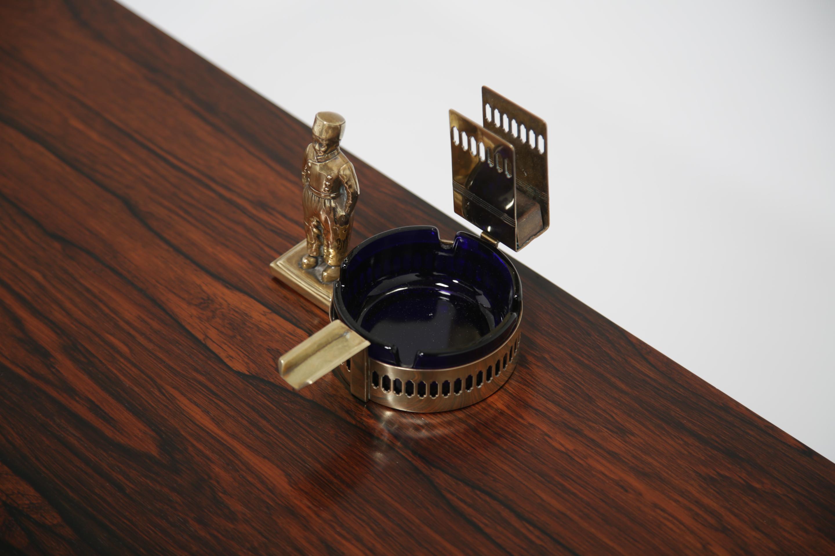 Cendrier Art Déco français en laiton et verre bleu cobalt avec figure de Bellboy, années 1930

Ce cendrier Art déco français unique, datant des années 1930, est une combinaison frappante de forme et de fonction. Fabriqué en laiton et marqué
