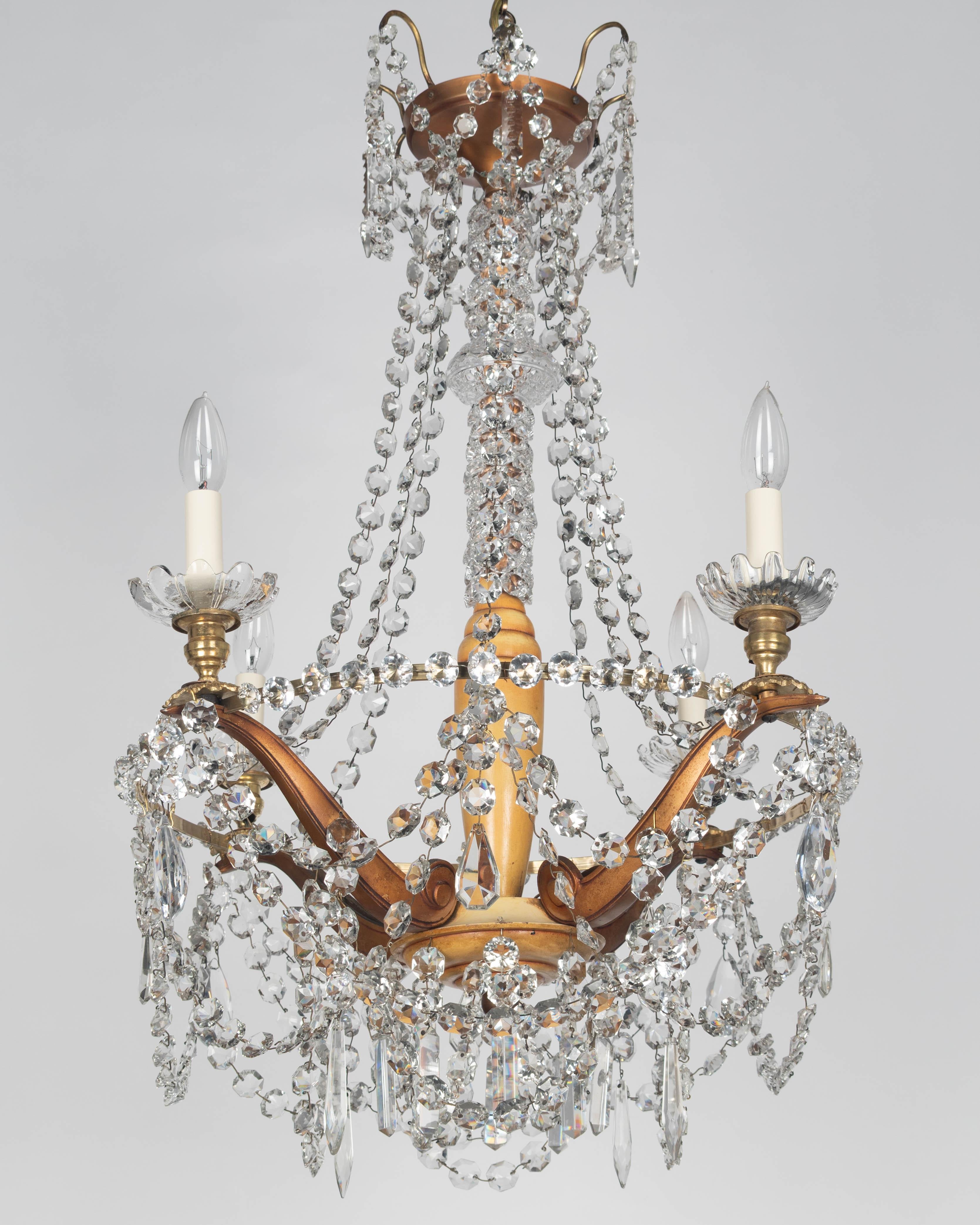 Lustre à quatre lumières de style Art déco français, avec des chaînes de perles en cristal taillé et une variété de prismes suspendus. Cadre solide en laiton patiné avec une grande colonne centrale en bois tourné. Les boules de verre sont toutes