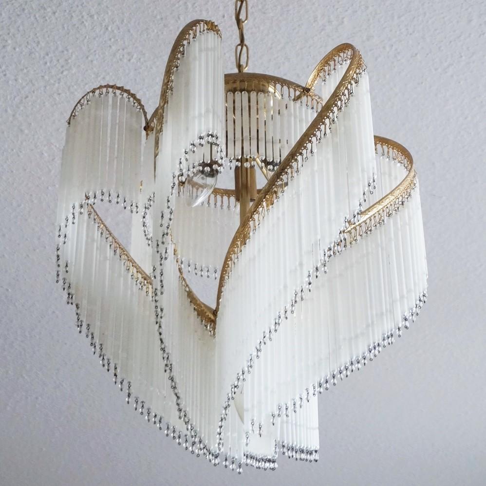 A lovely Art Deco brass cascading etched glass rod chandelier, France, midcentury. The numerous etched glass rods with glass beads give a great lighting effect creating a pleasant brightness atmosphere.
The chandelier has been cleaned to its