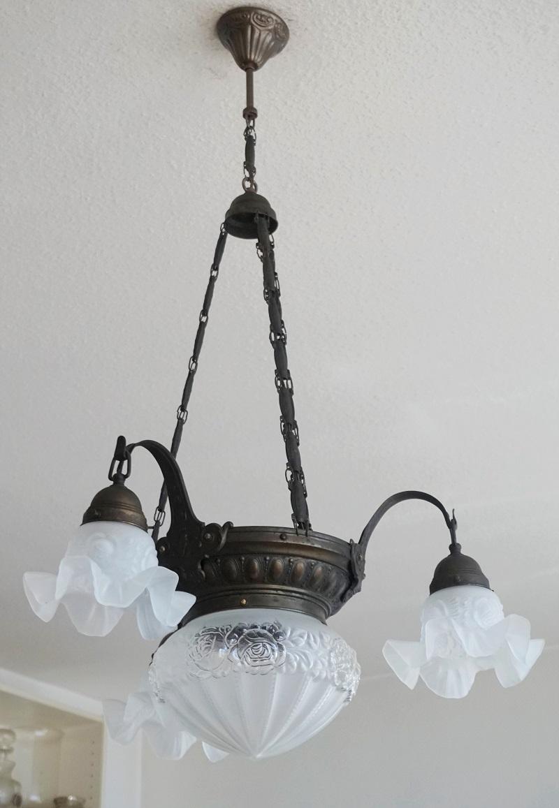 A lovely French Art Deco brass and high relief frosted glass chandelier. Beautiful globe in the center surrounded by three curved lamp arms with tulip shades, France, 1930-1935. This wonderful chandelier is Fine original condition, aged patina to