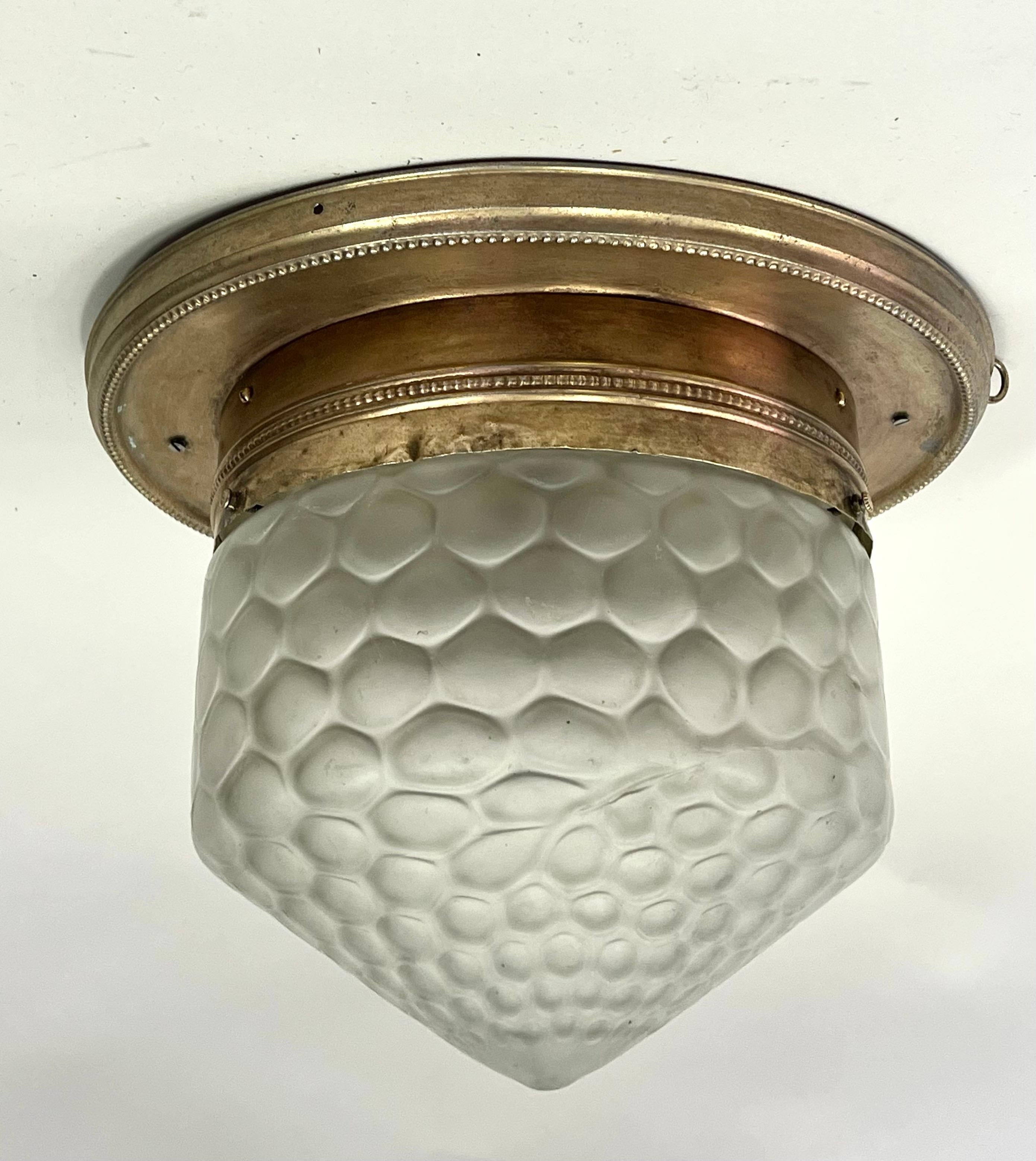 An Elegant and Classic French Art Deco / Early Mid-Century Modern Flush Mount fixture or pendant in the style of Emile-Jacques Ruhlmann. The brass is composed of an antique brass round frame featuring a minimal egg and dart motif. The satin glass