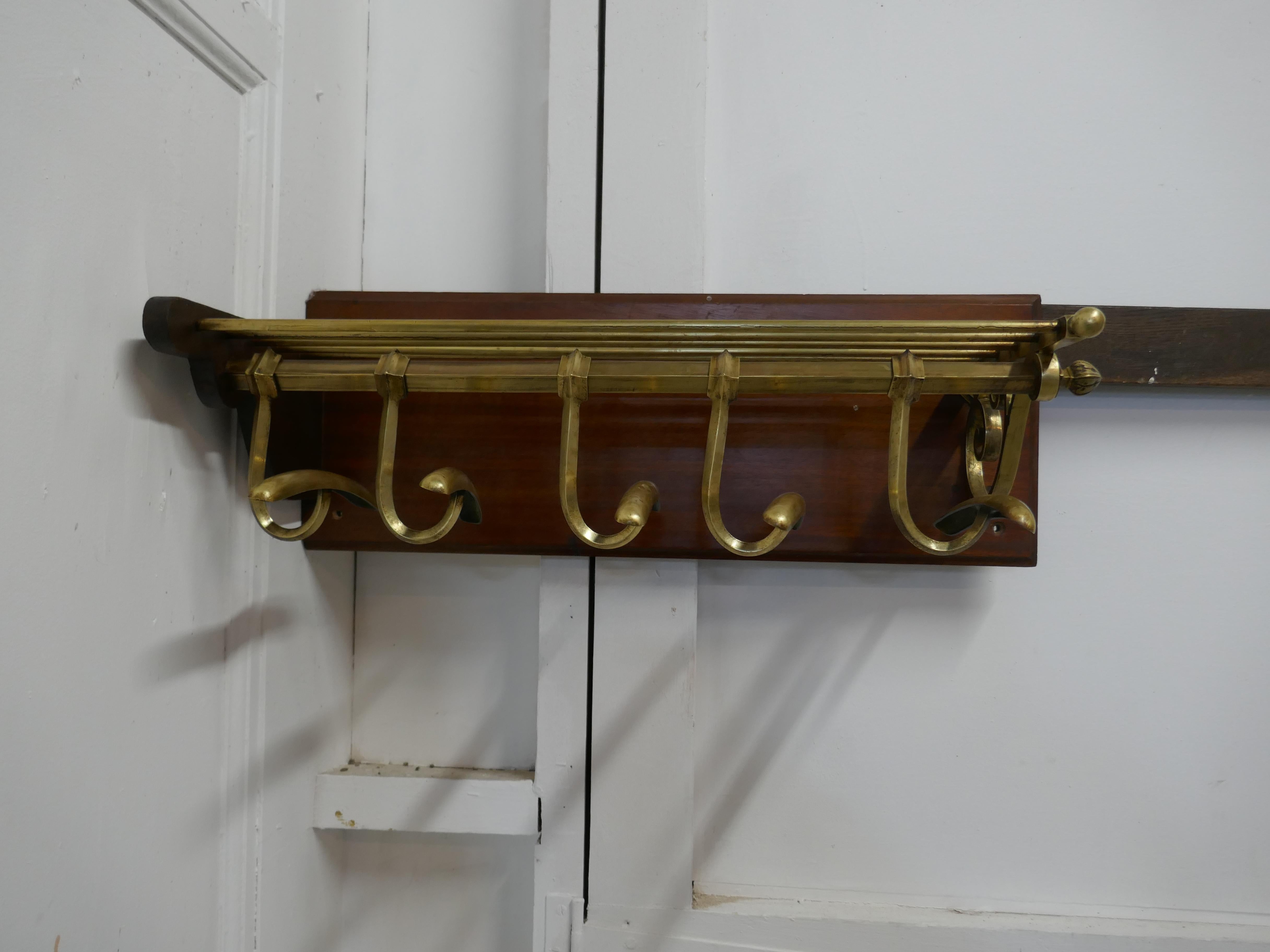 French Art Deco brass hat and coat rack, Pullman Railway train style

 This Art Deco style hat and coat rack has 5 sliding hooks and an upper railed shelf. This is a corner fitting piece. With one scroll end and it is fitted on a mahogany back