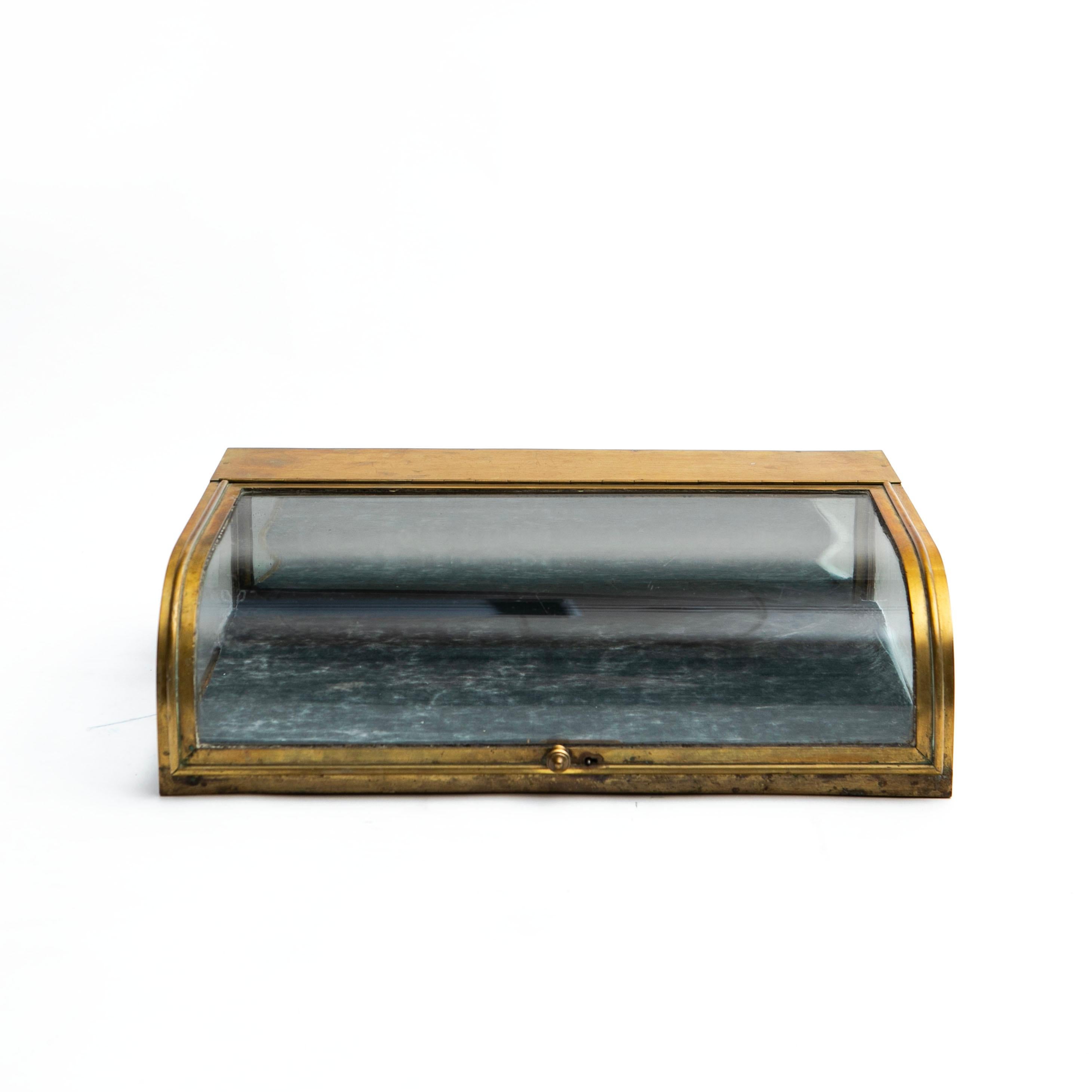 French art deco table display case / montre, made of glass and quality brass.
Brass frame with classic curved glass door and glass sides.
The bottom is covered with velour (this can be easily replaced).

In untouched good condition with natural