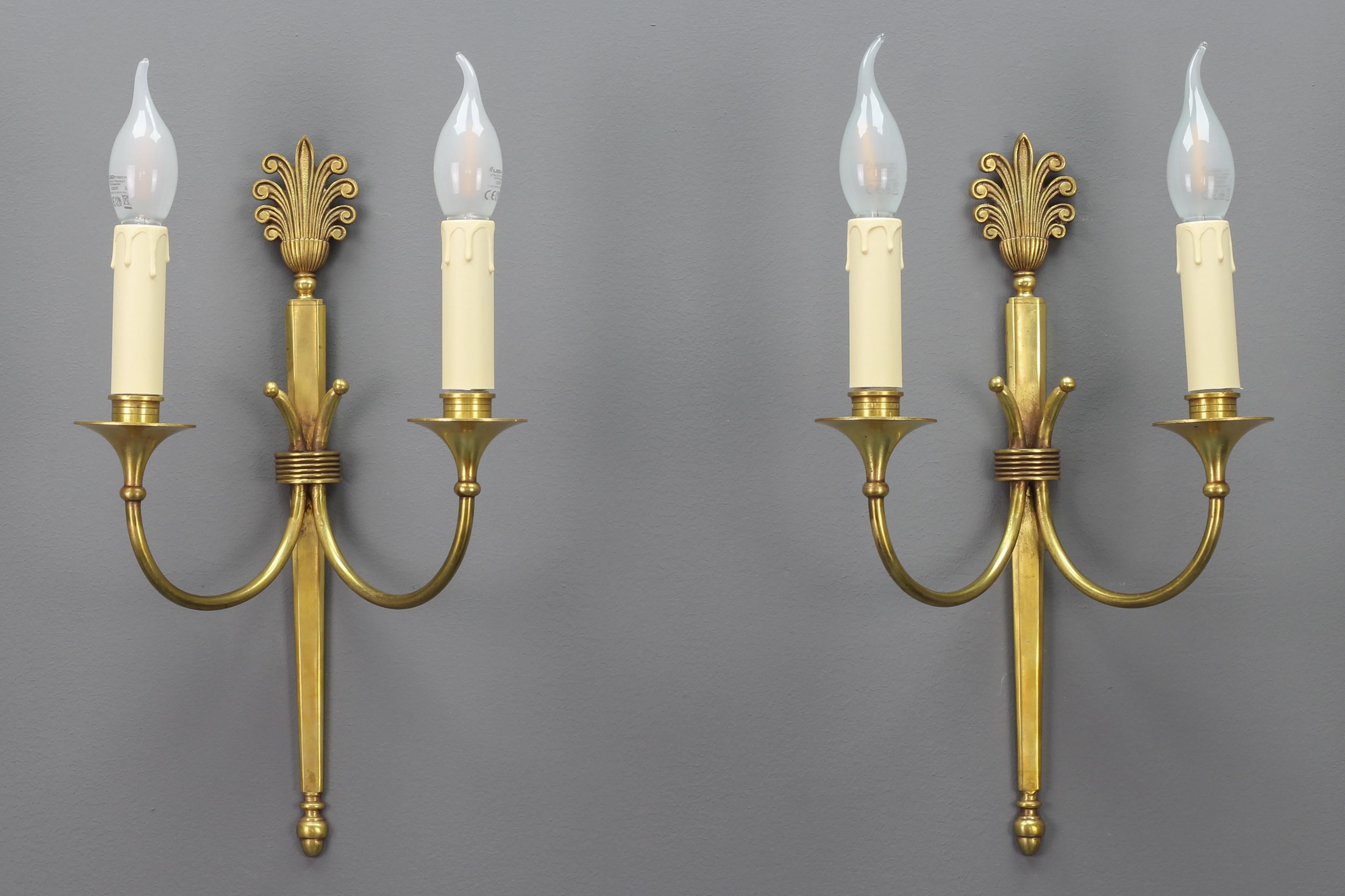 Pair of French Art Deco brass twin arm sconces from ca. 1930.
This elegant pair of brass sconces has a beautiful brass base with typical Art Deco-style decors. Each sconce has two arms each with a socket for E14 size light bulb. Numbered at the