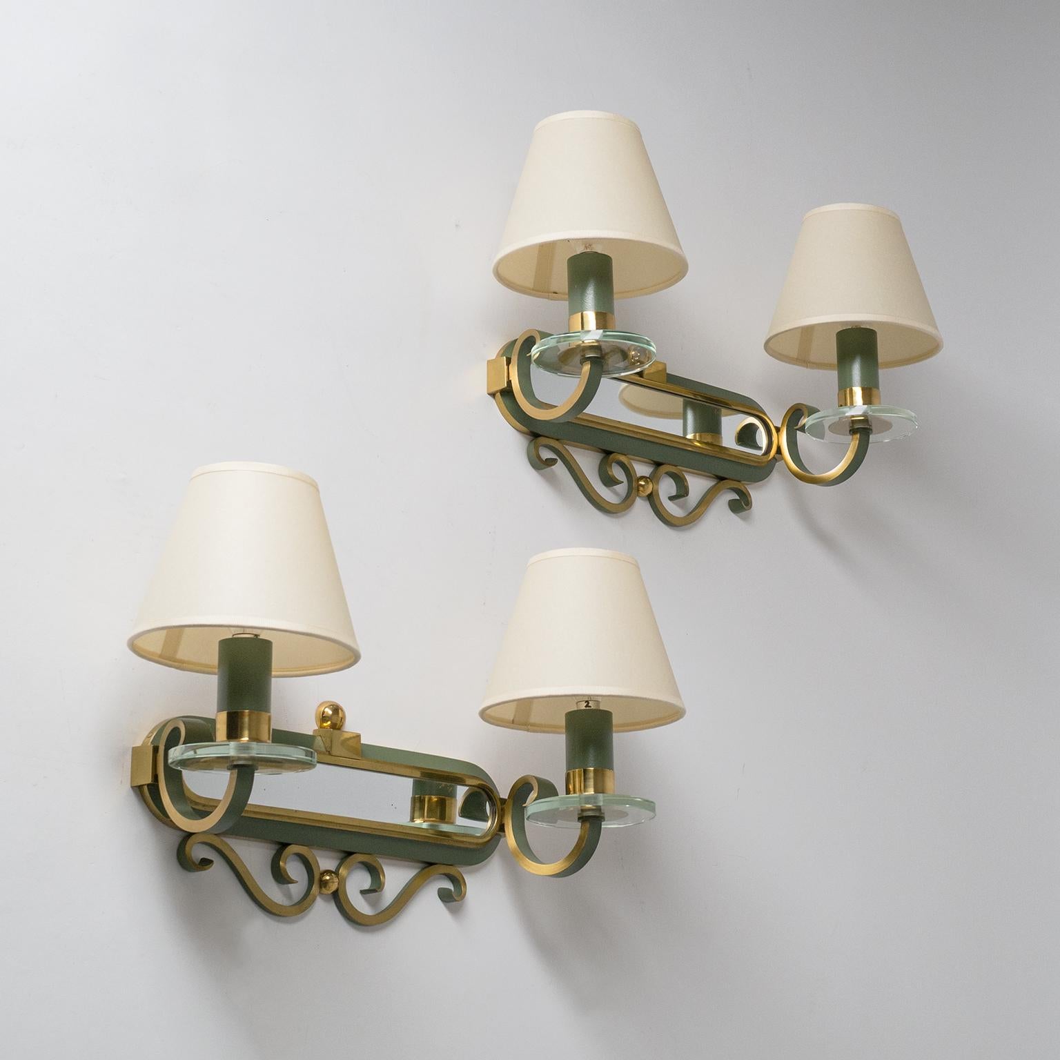 Fine pair of large French Art Deco wall lights from the 1940s. Built entirely in brass combining various finishes: polished, brushed and lacquered in a pastel olive color. In addition each arm sports a glass disc and the backplates have a mirror