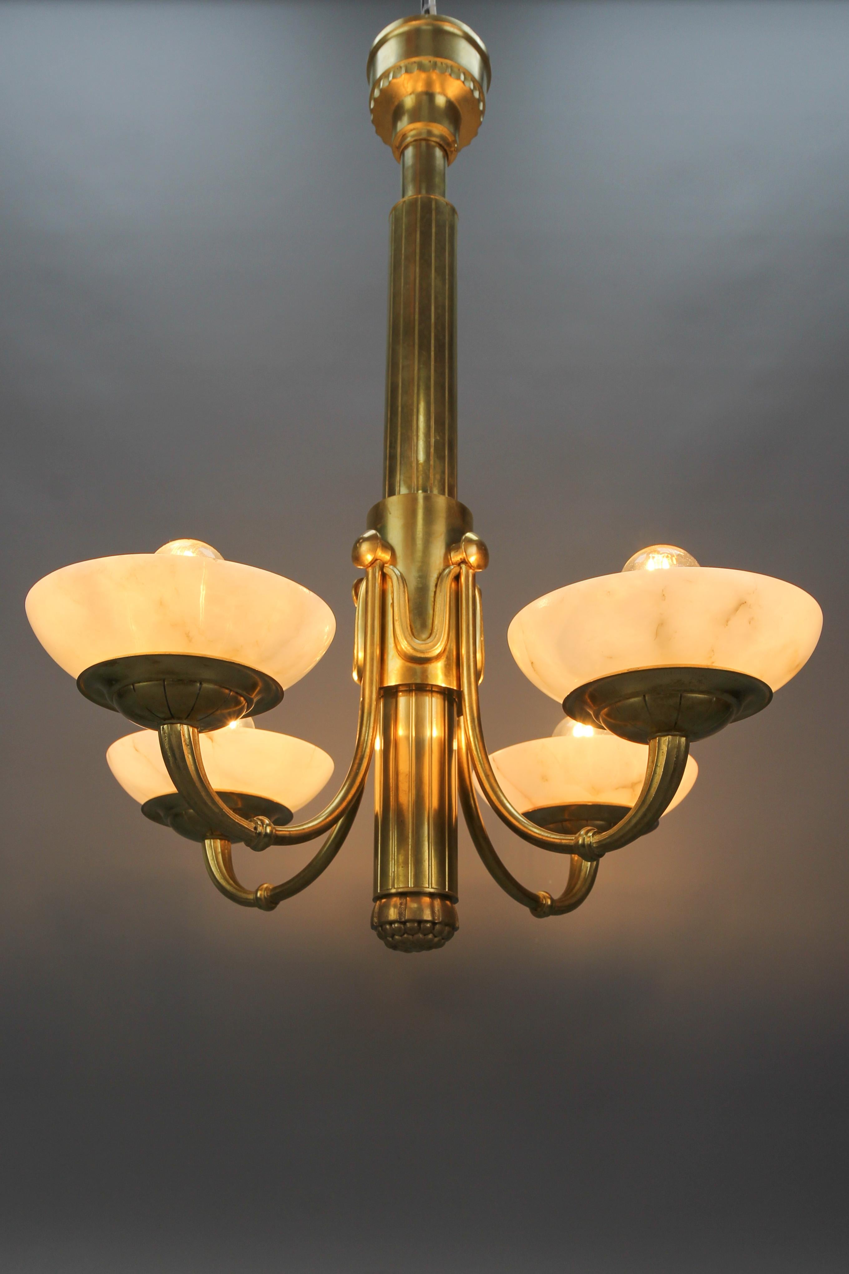 French Art Deco bronze and alabaster four-light chandelier from ca. 1920.
This elegant and classical Art Deco chandelier features a bronze and brass frame - a monumental central stem with four arms, each with a lampshade made of creamy white