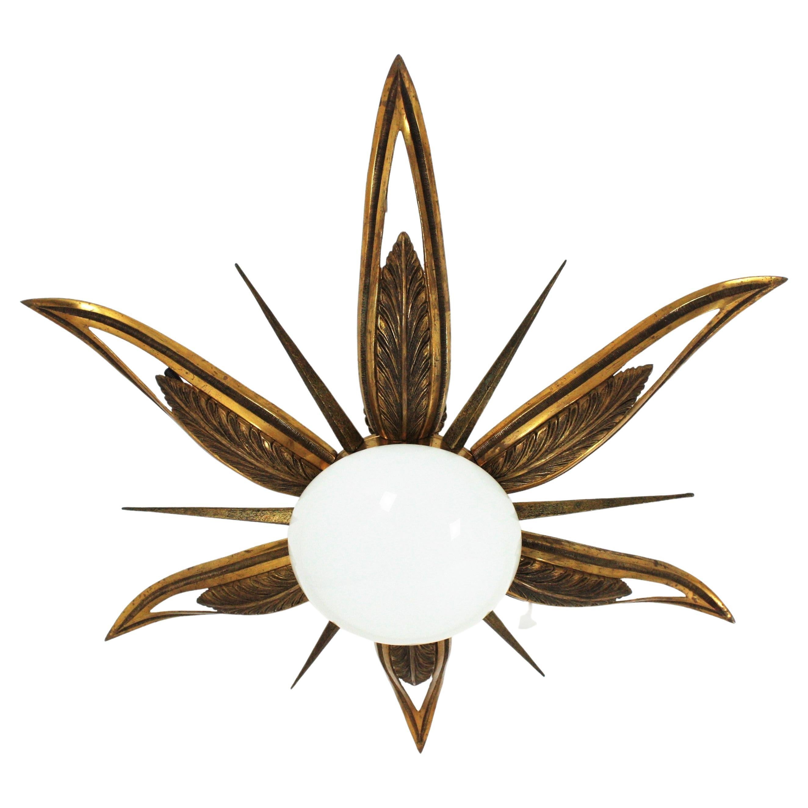 An exceptional Art Deco starburst shaped engraved and molded bronze ceiling lamp, France, 1930s.
This flush mount features a flower burst or starburst with 6 large leaves or rays, 6 pointed smaller and thinner rays and an opaline white glass