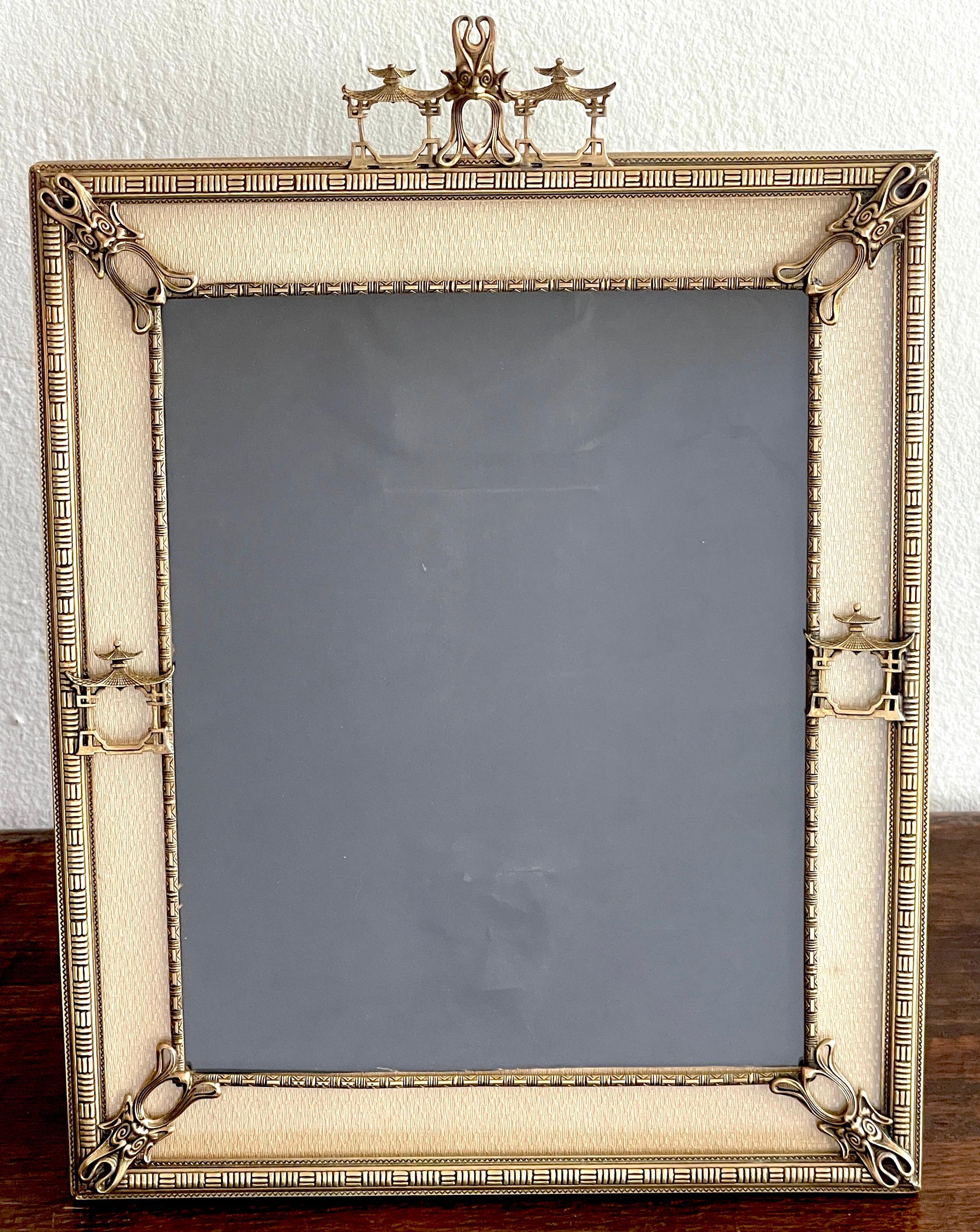 French Art Deco Bronze Chinoiserie Stye Frame
Of rectangular form, with a centered bronze open mouthed Chinese mask, flanked by two models of pagodas. The surround retains its orignal subtle fabric surround with the four Chinese mask at each corner