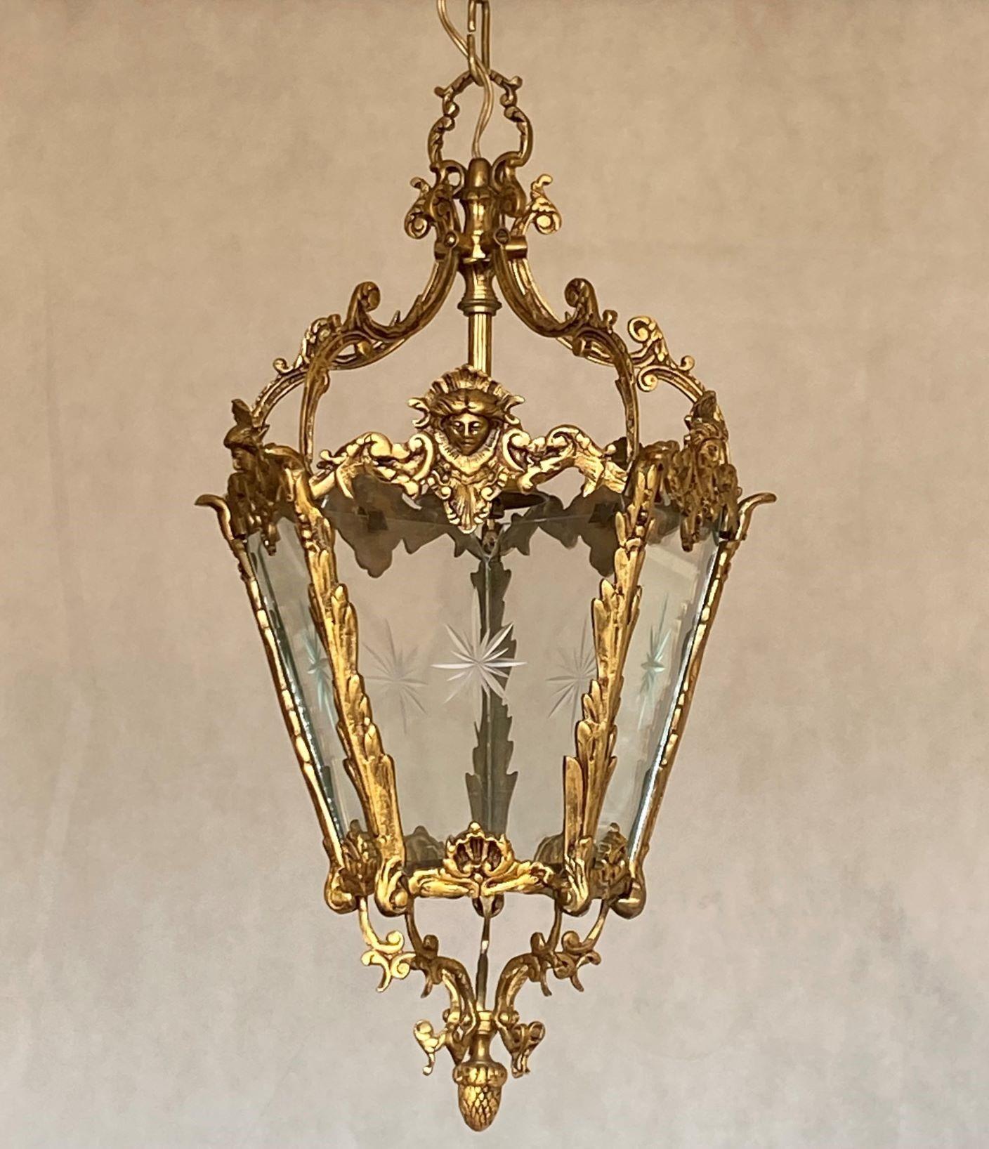 A lovely French Art Deco period bronze and cut glass hall lantern, France, 1910-1920. Bronze beautifully decorated with faces, five glass panels with a cut star design. The lantern is in very good, condition, aged patina to bronze, rewired
With a