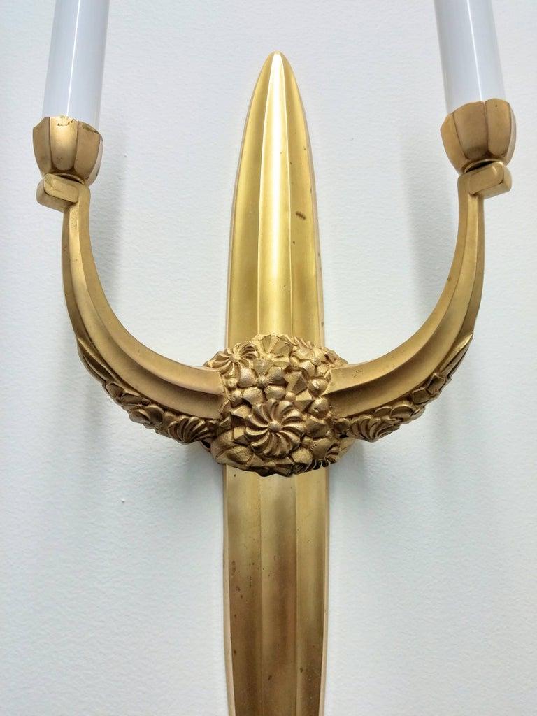 These stunning gold pair of French Art Deco style wall sconces are attributed to “Sue et Mare”. Each sconce elongated ovoid fluted with a floral mount to center emanating two arms bearing candle mounts. Sconces have been rewired for U.S. standards.