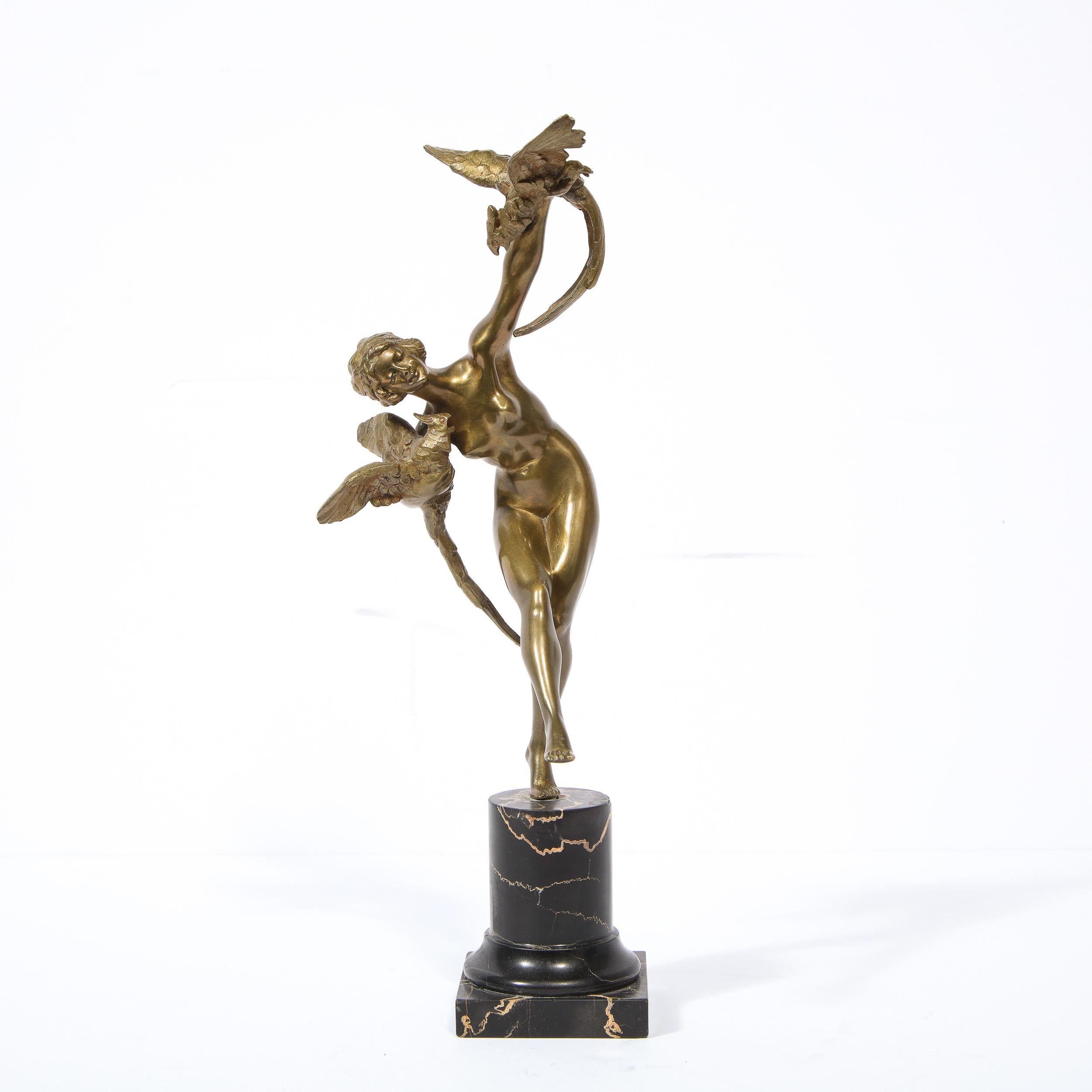 This stunning Art Deco sculpture was produced in France, circa 1930 and procured in Buenos Aires, Argentina. It features a dancing nude female form in bronze holding a pheasant in each arm. The piece sits on a cylindrical exotic black marble