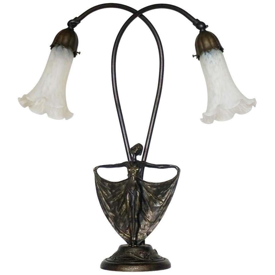 Art Deco bronze figurine double arm table lamp with white art glass tulip shades, France, circa 1930-1939. The adjustable two arms allow variable settings and width.
This wonderful table lamp is in very good condition, with beautiful patina,