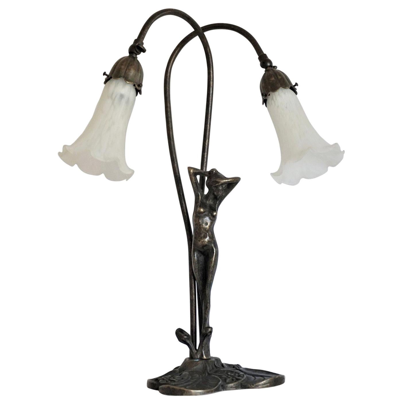 Art Deco bronze figurine double arm table lamp with white art glass tulip shades, France, circa 1930-1939. The adjustable two arms allow variable settings and width.
This wonderful table lamp is in very good condition, with beautiful patina,