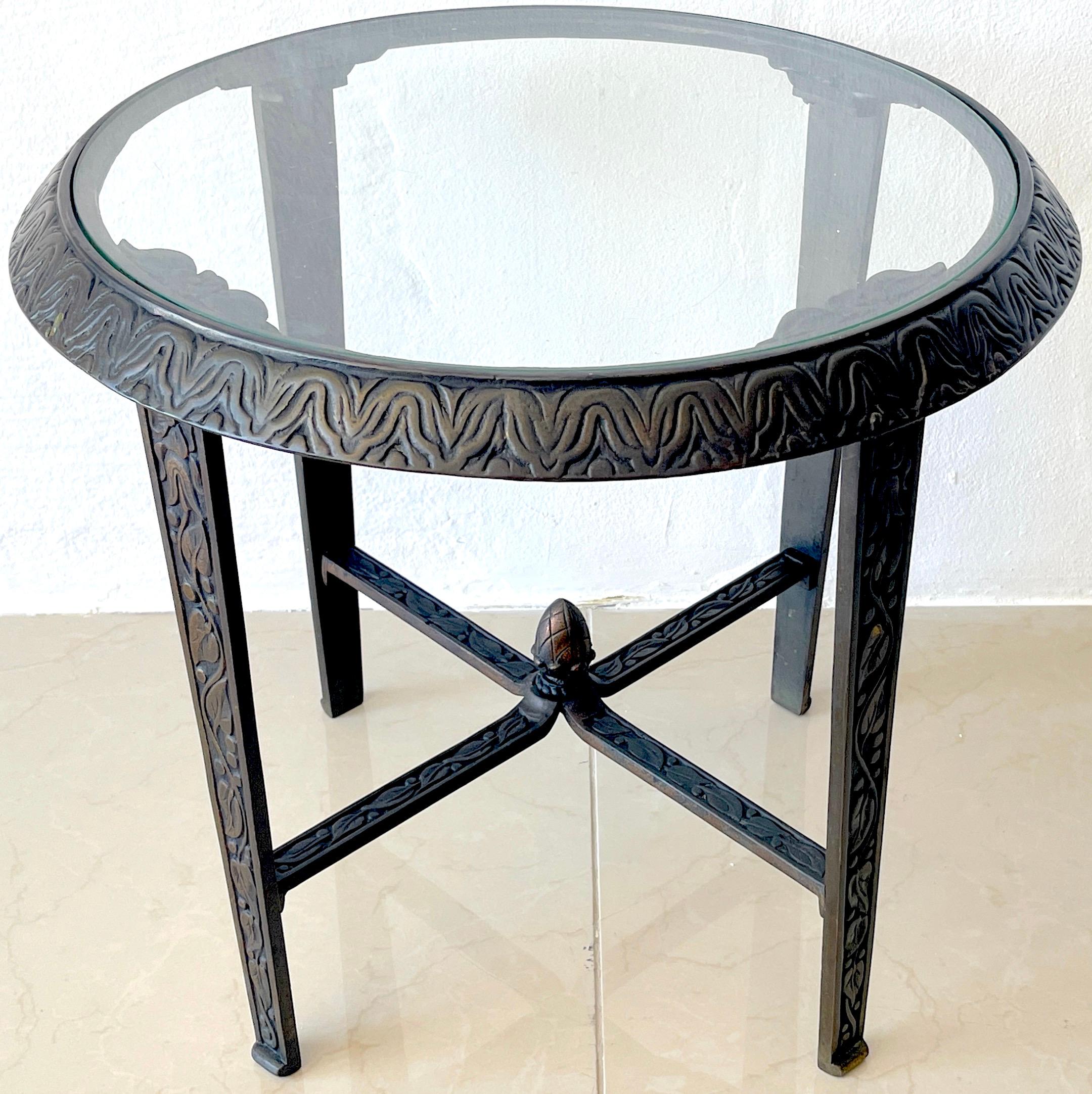 French Art Deco bronze & glass side table, style of Edgar Brandt. With inset 18-Inch diameter clear glass top, Beautifully cast with stylized architectural elements, leaves, berries, raised on four columnar legs joined with an 'x' stretcher with