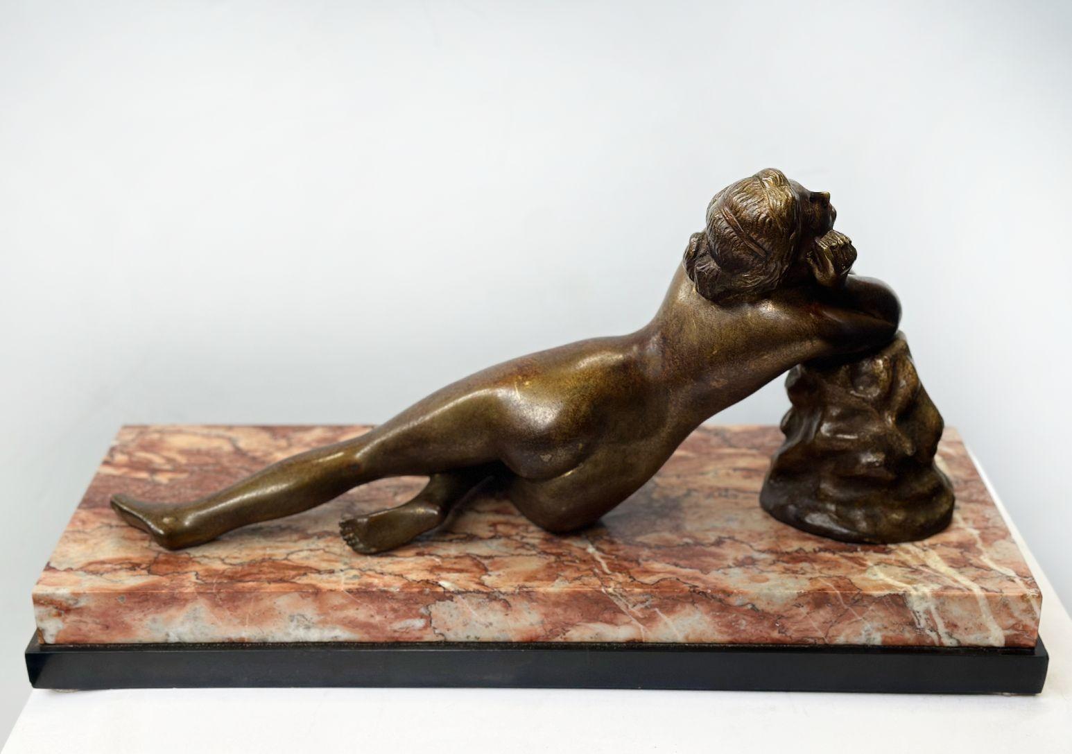 Alluring Art Deco patinated bronze nude sculpture laying gracefully on a marble and onyx base, while also reclining on a bronze rock figure. Made in France, 20th Century.
Dimensions:
10