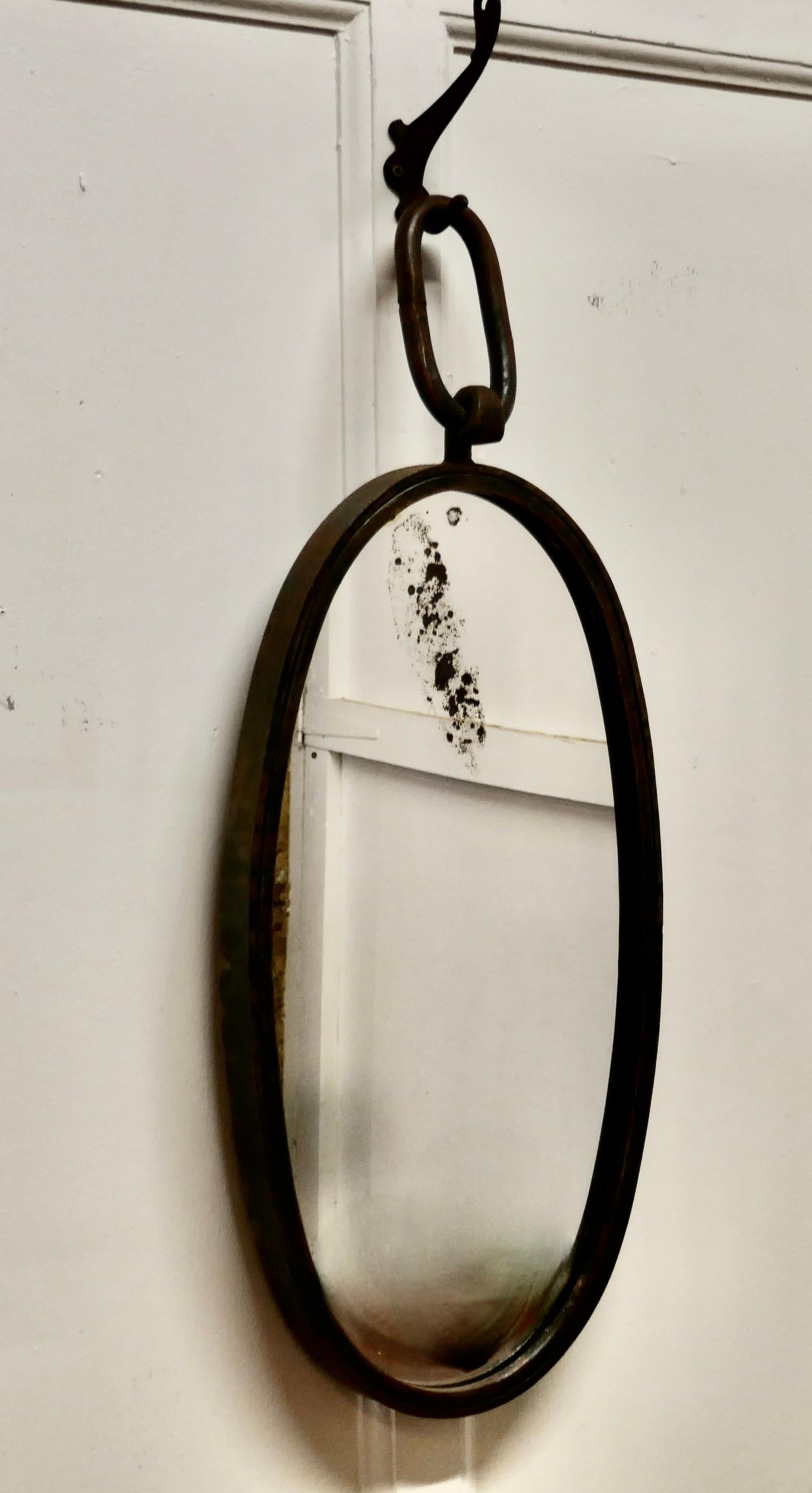French Art Deco Brutalist oval iron ships mirror

This an Art Deco period piece it is oval in shape and resembles a ships block, it hangs on a large iron link
A great piece on a shipping theme with slightly rusty finish and a foxed patch near the