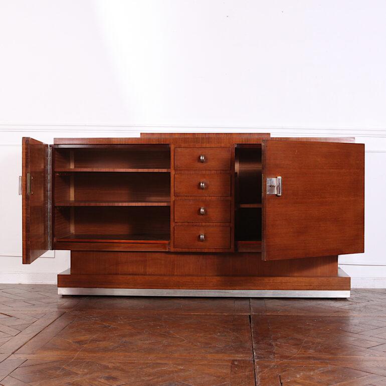 A striking French Art Deco exotic wood buffet of stepped geometric form, having two doors flanking a centre bank of five drawers, all retaining their original nickle-plated pulls. Plinth base with brushed metal trim. C. 1930.