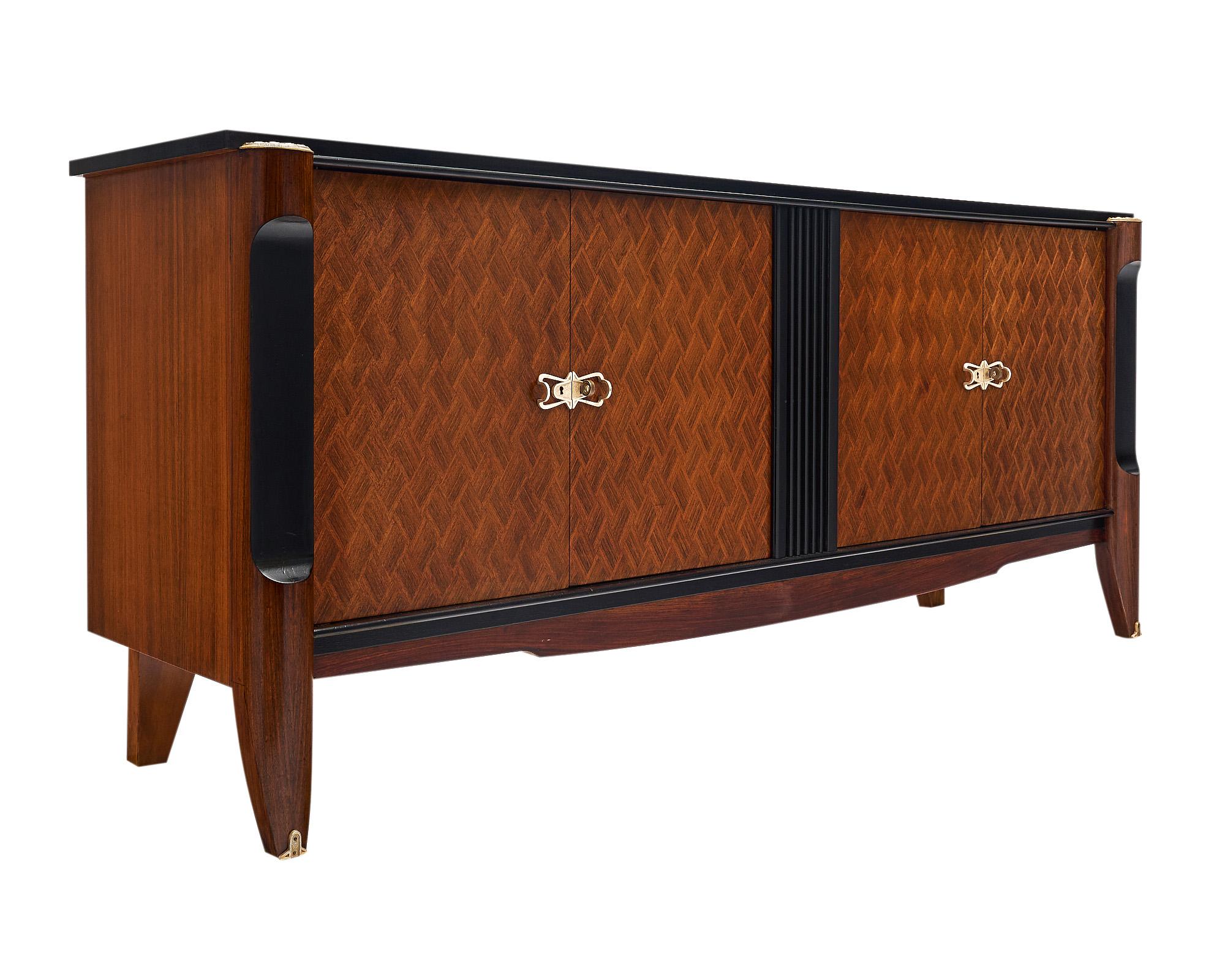 Buffet, in the Art Deco style from France. This piece features a beautiful chevron patterned parquetry across the four doors and ebonized details throughout. The doors and legs have the original gilt brass hardware. The four doors open to reveal