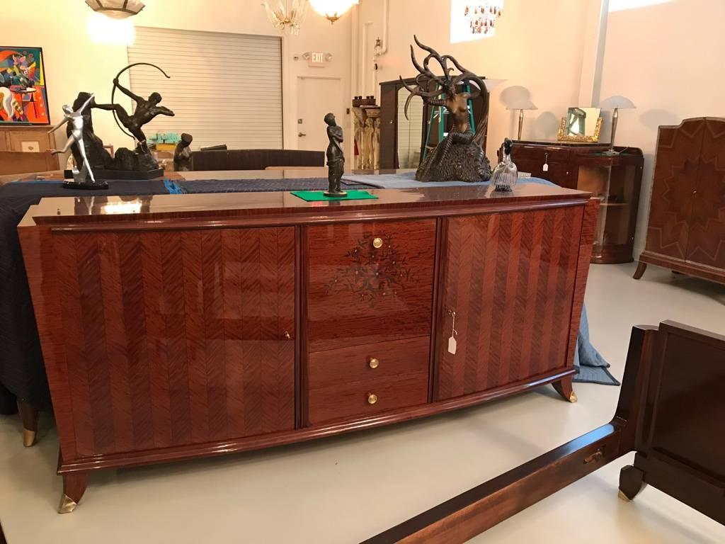 Grand French Art Deco marquetry buffet with a center drop down mirror dry bar. Having beautiful floral marquetry inlay and stunning brass hardware. The center door drops down to reveal a mirrored dry bar. Flanked by two large cabinet doors. Has been