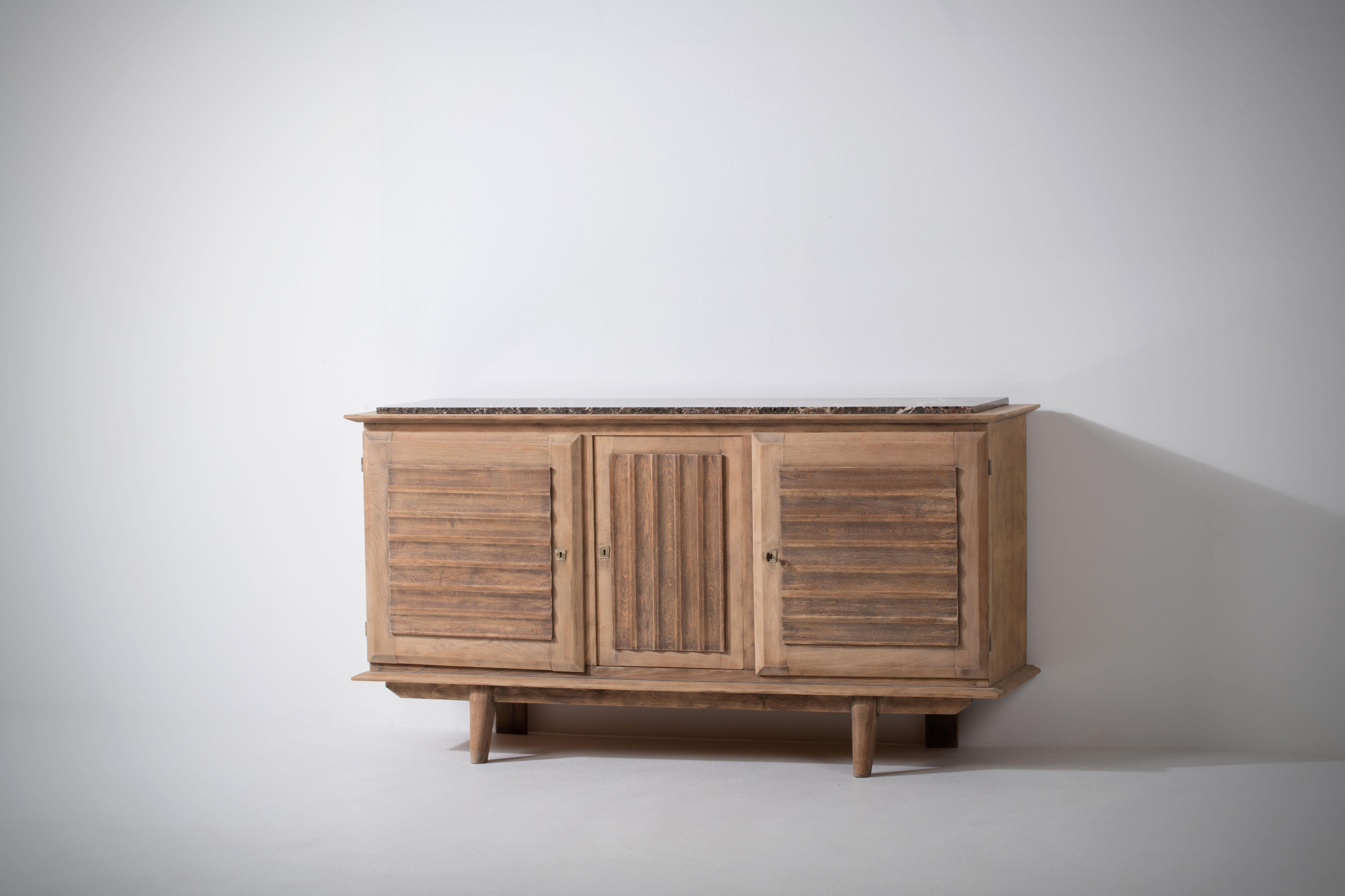 Introducing a stunning French Art Deco buffet from the 1940s, crafted with exquisite natural oak and crowned with a luxurious marble top. This exceptional piece showcases the elegance and sophistication of the Art Deco era, with its scalloped