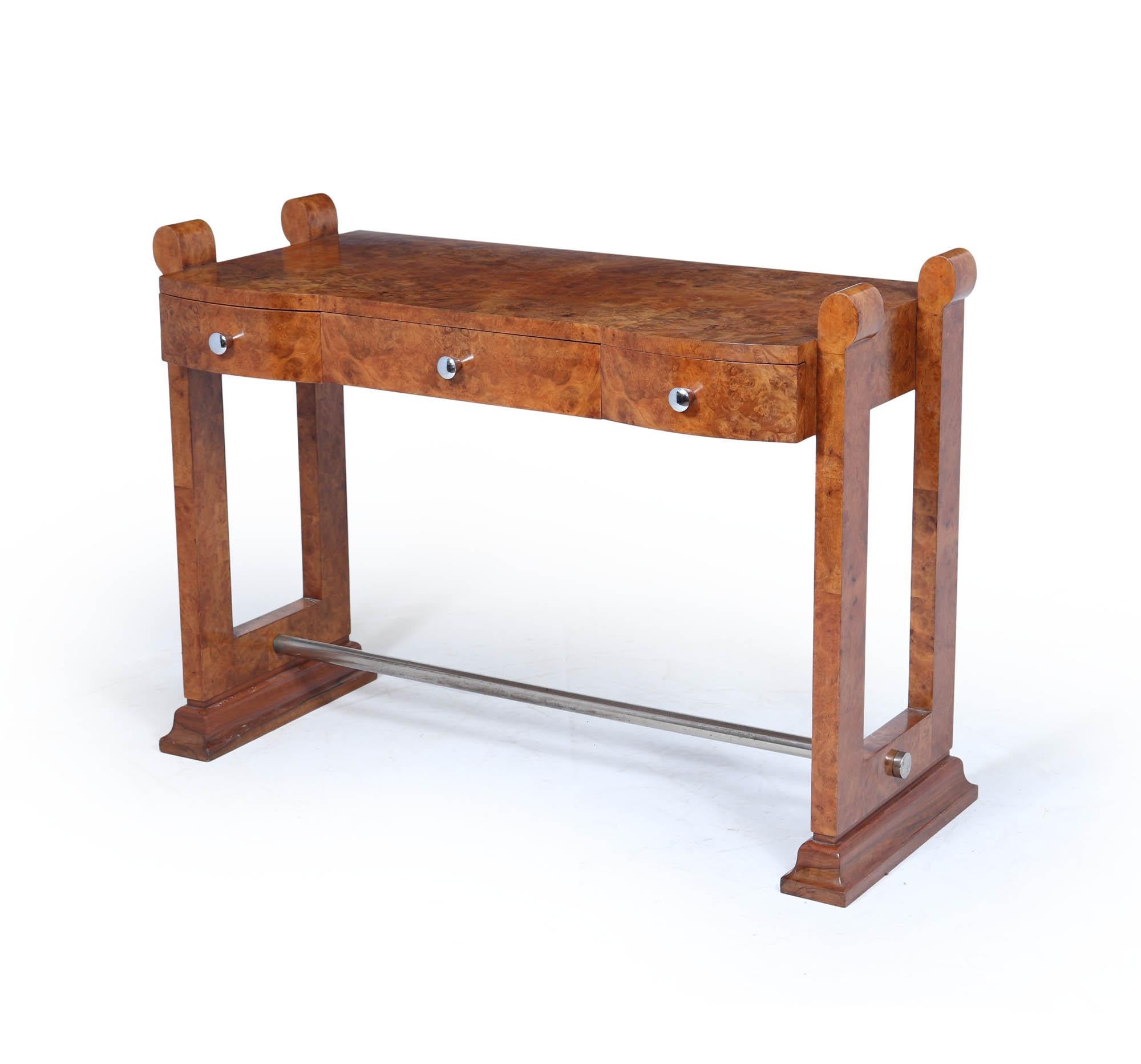 Art Deco Console Table
A striking French Art Deco console or side table dating to the 1930s, finished in rich burr maple veneer. The piece is defined by its architectural profile with open rectangular legs, chrome stretcher bar, and distinctive