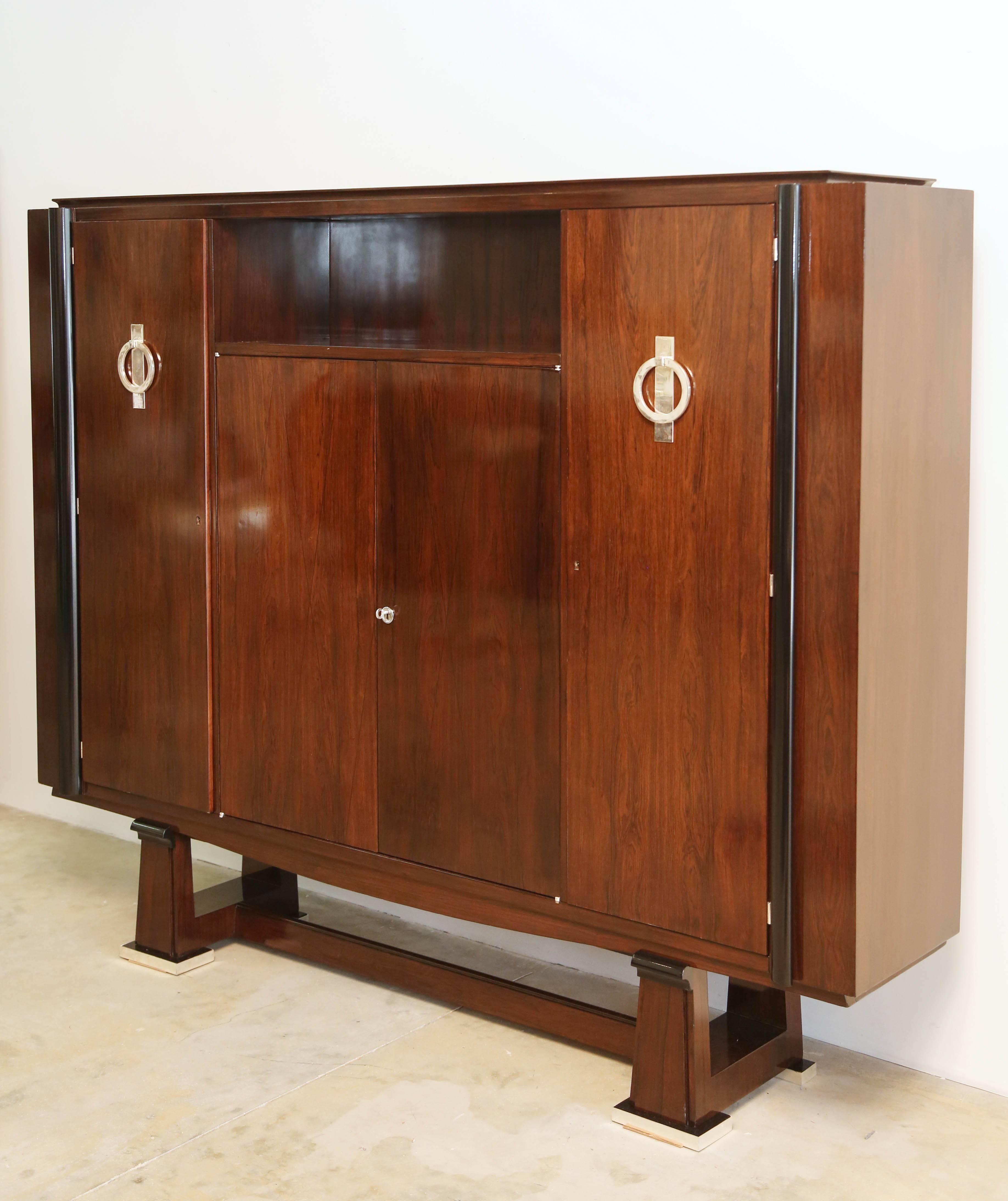 Exceptional quality piece of furniture in rosewood,
(Palissandre) Art Deco period,
standing on a base ending by four rectangular feet each one encased in a nickel plated metal parts.
Two thick metal rings on each front doors.
This piece is an
