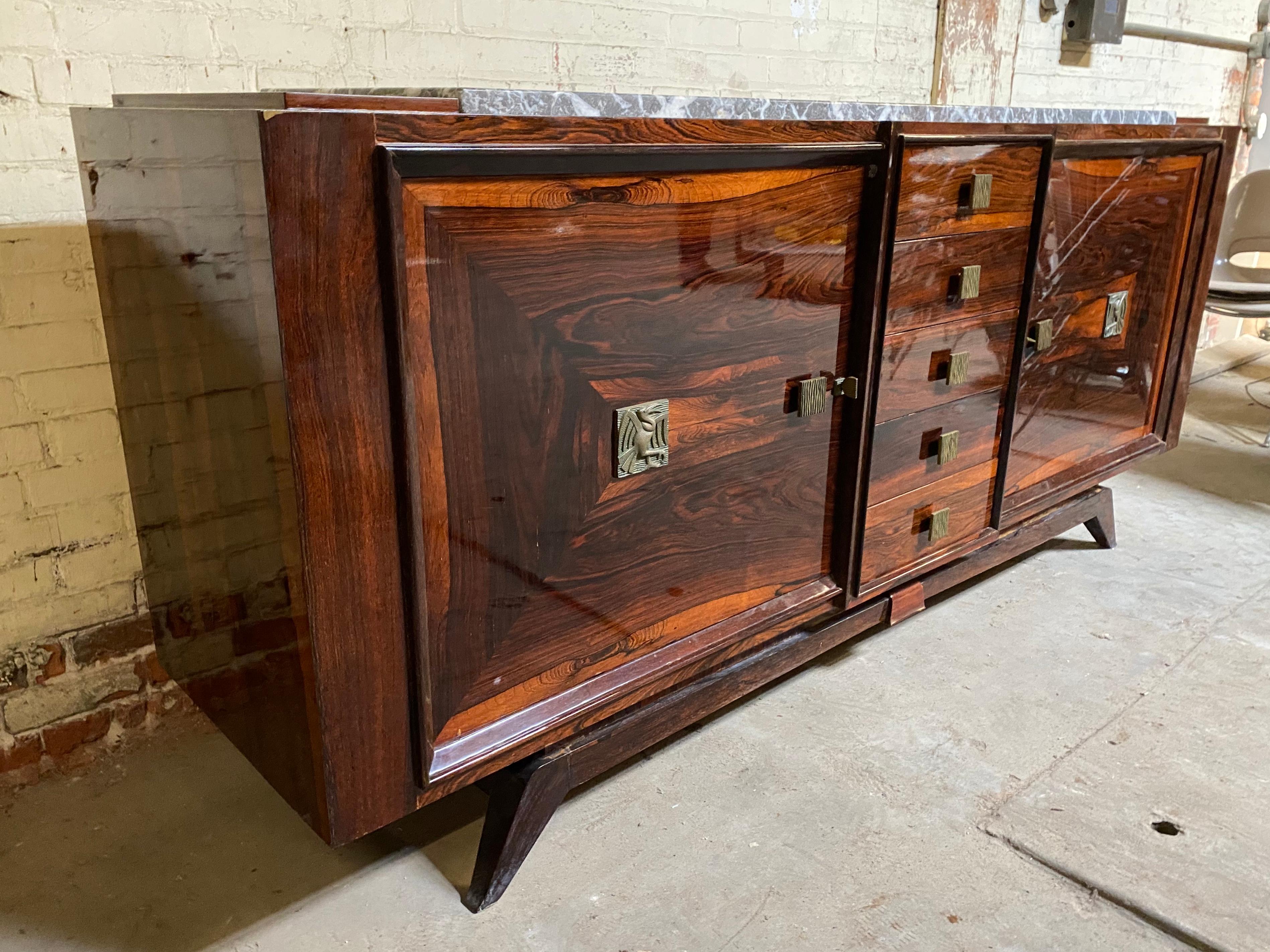 Stunning French Art Deco cabinet / sideboard done in striking grained Macassar ebony, featuring cabinet door pulls in cast bronze depicting stylized birds, and modernist drawer pulls, also retains white with gray marble top. Would surely enhance any