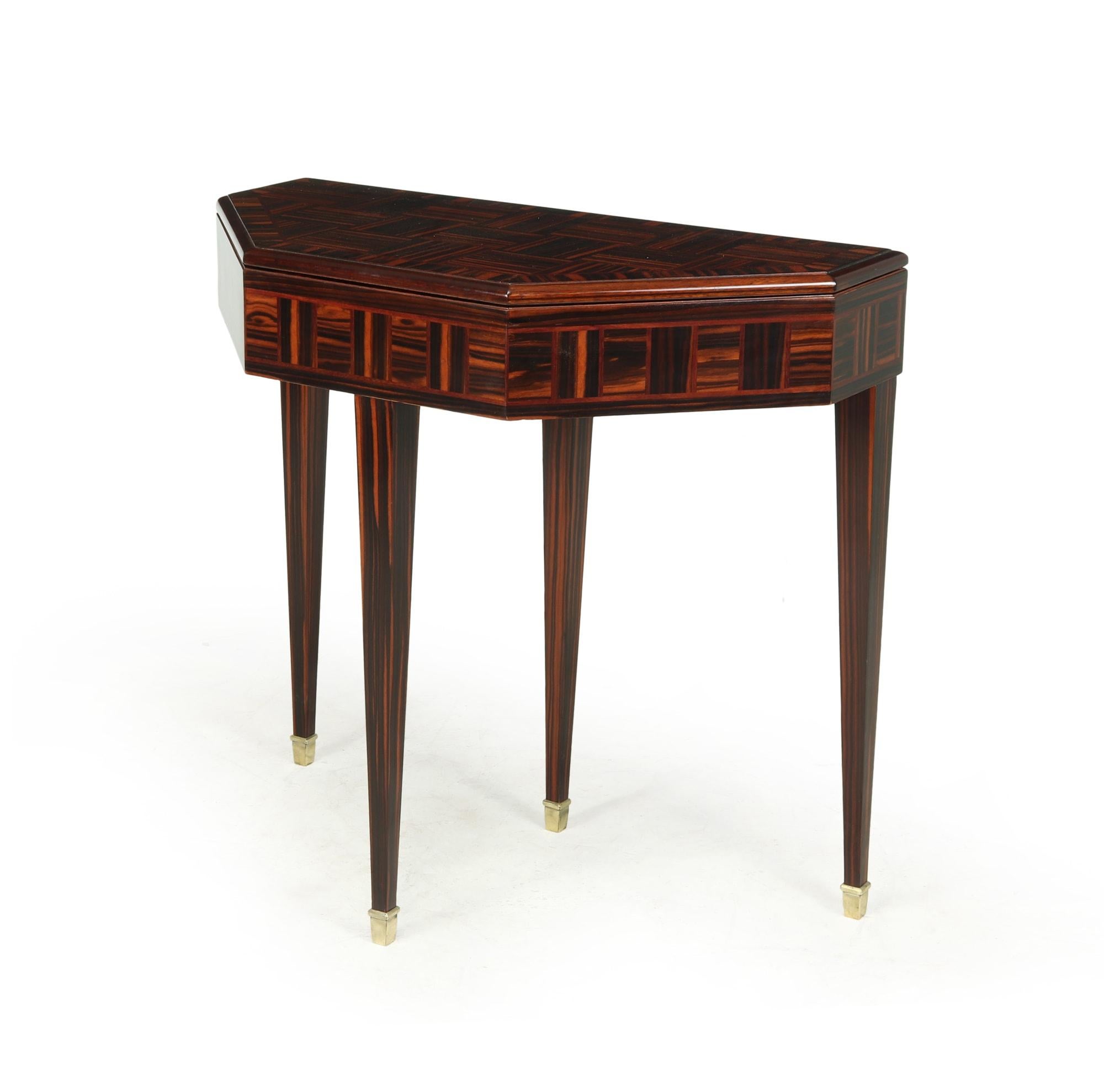 A fold over card table produced in the 1920’s in France from parquet Macassar ebony, fold over top that has been baize lined slide out drawer and support on four tapered square legs terminating with brass sabots.

The table has been fully polished