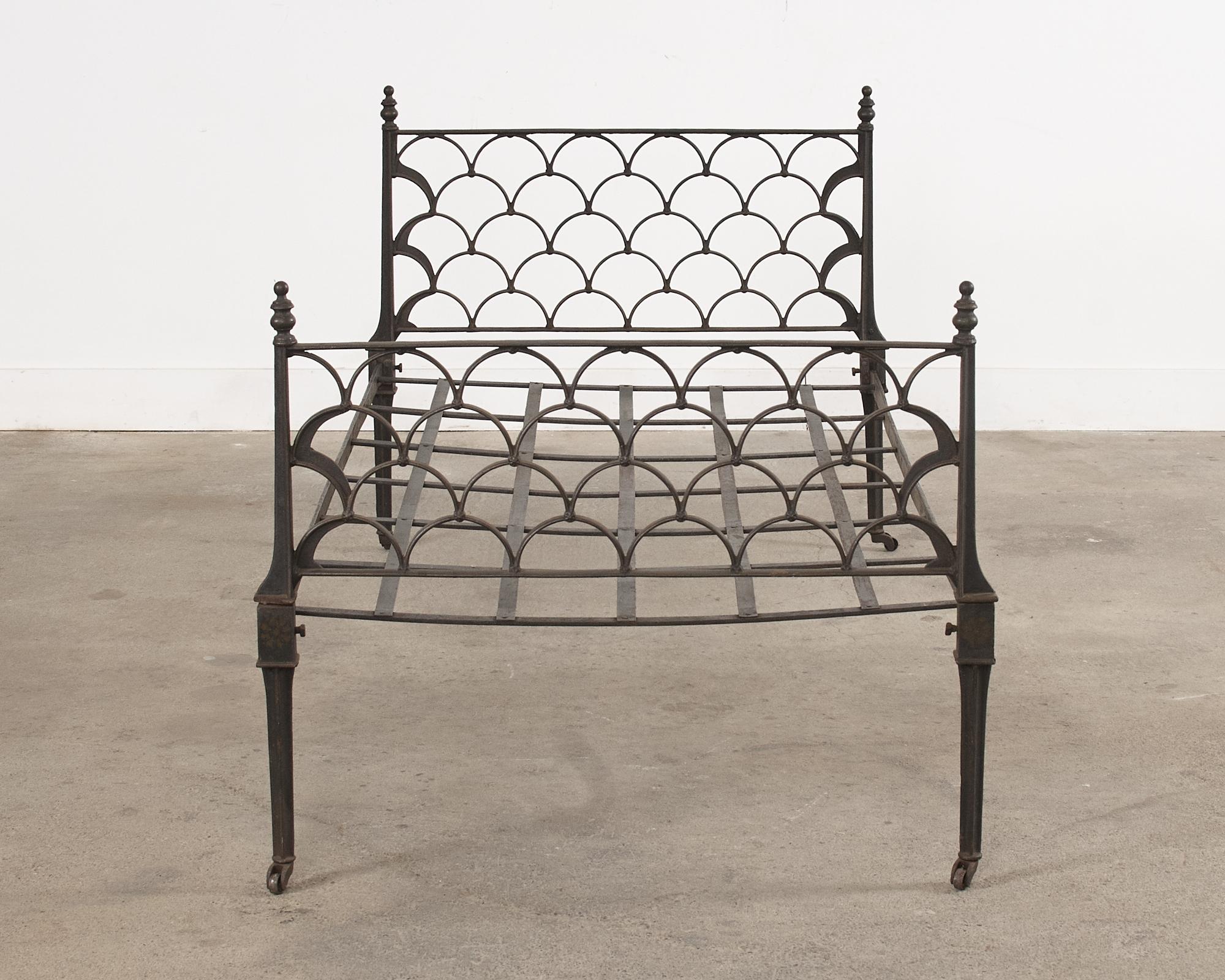 Distinctive French art deco daybed constructed from cast iron. The bed features a headboard and footboard decorated with gracefully curved arches in a geometric pattern. The corners of the bed have graduating round finials. The bed is supported by