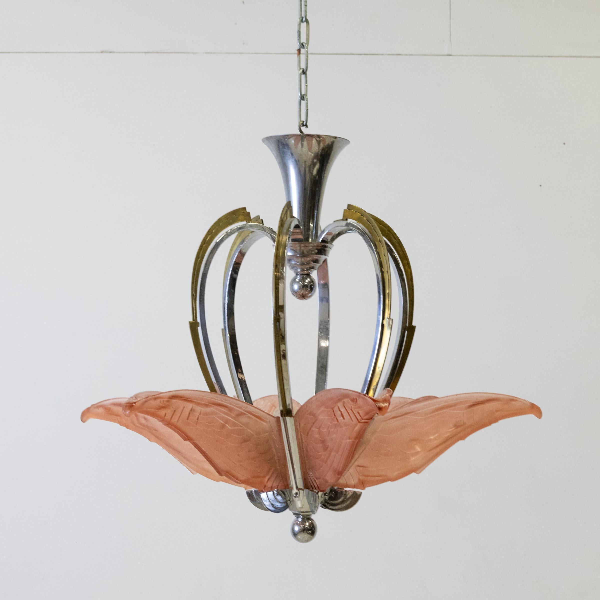 Questo straordinario lampadario è una creazione originale di P. Maynadier.

Sei pannelli di vetro color blush, ciascuno inciso con un suggestivo uccello geometrico in volo, emblema di libertà, grazia e progresso, circondano l'apparecchio. Questi
