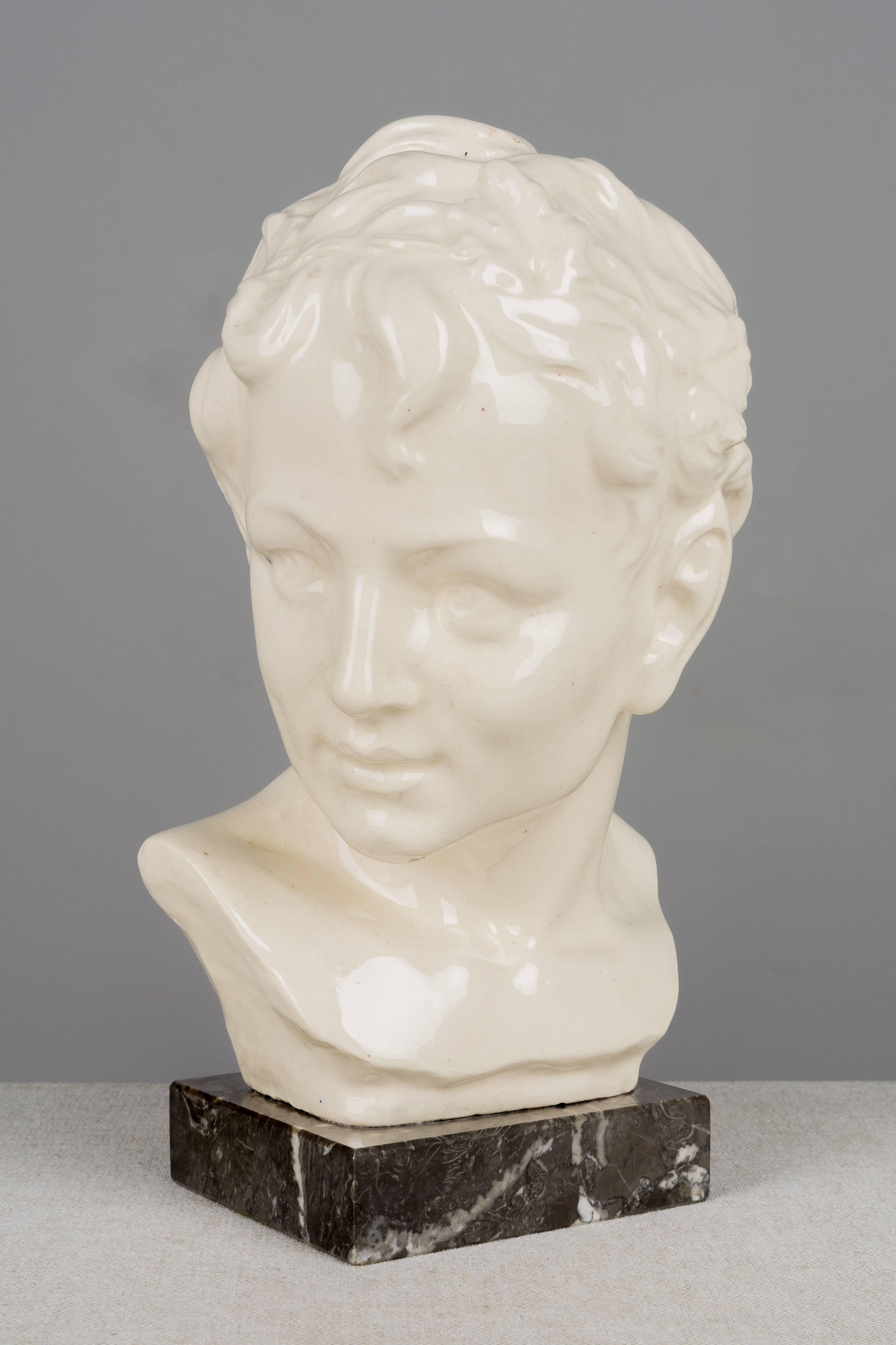 A French Art Deco craquelé ceramic bust of a young faun with pointed ears and a garland of leaves on his head. Marble base. Weight: 4.5 lbs. Please refer to photos for more details. We have a large selection of French antiques at Olivier Fleury,