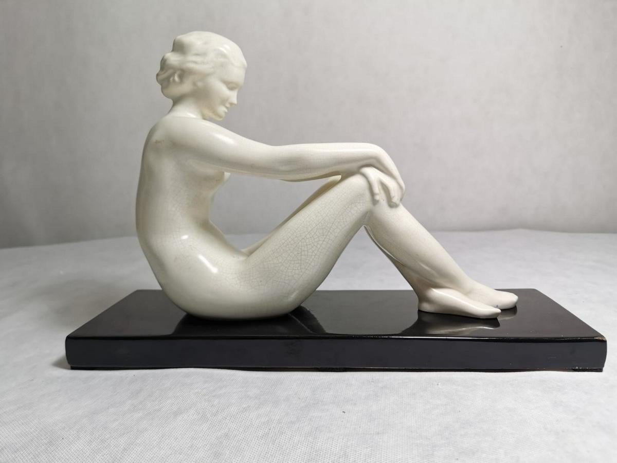An Art Decò statue in craquelé ceramic (Crackle glazed ceramic) produced in France in 1930, the massive base is completely in black ceramic, the figure of a woman is in a fluid pose, very graceful and gentle, the craquelé effect makes the object