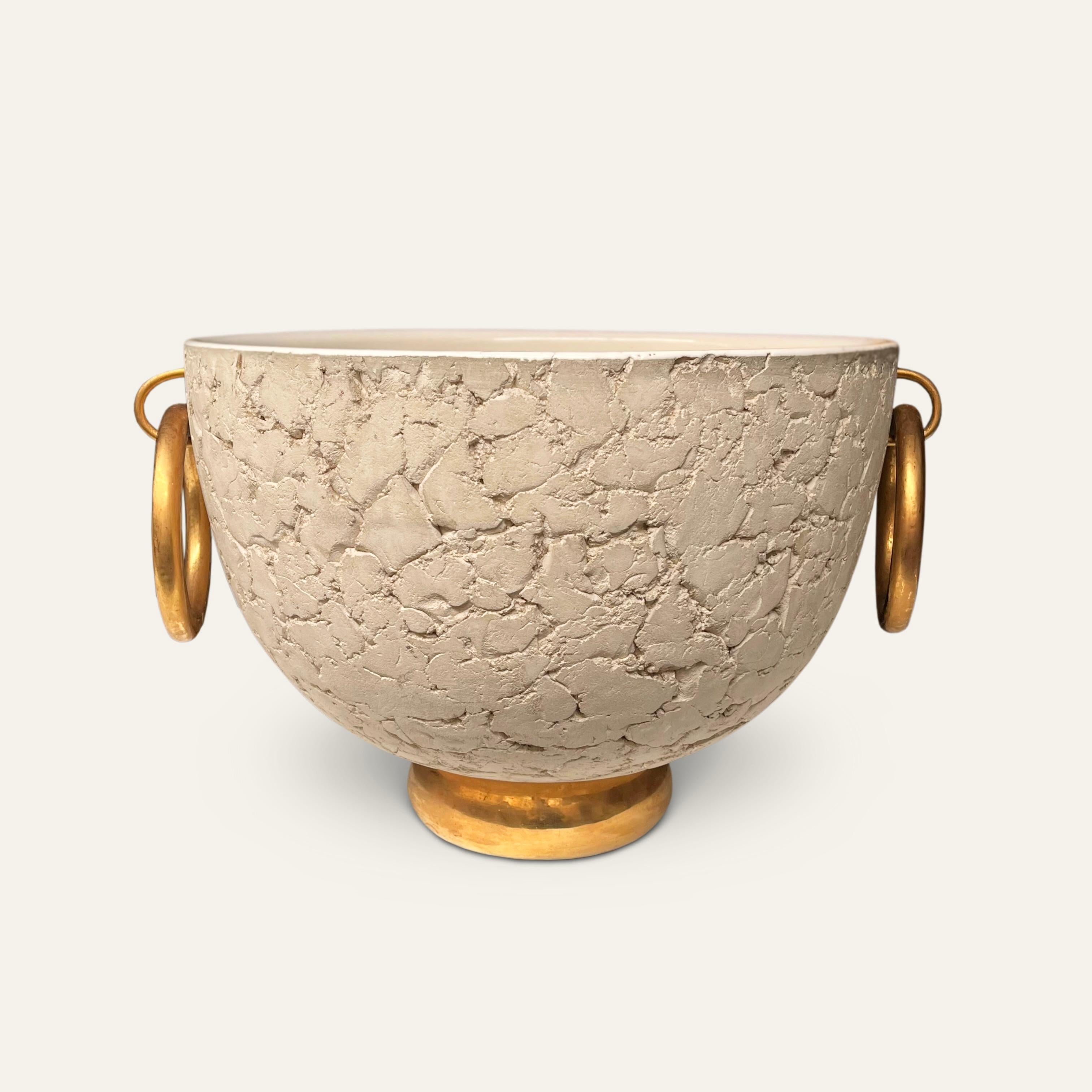 Una grande fioriera in ceramica art déco degli anni '30 attribuita a Kaza.
Il corpo non smaltato pressato a mano con l'interno smaltato color crema poggia su una base con piedi dorati ed è rifinito con un classico bronzo dorato.  maniglie circolari