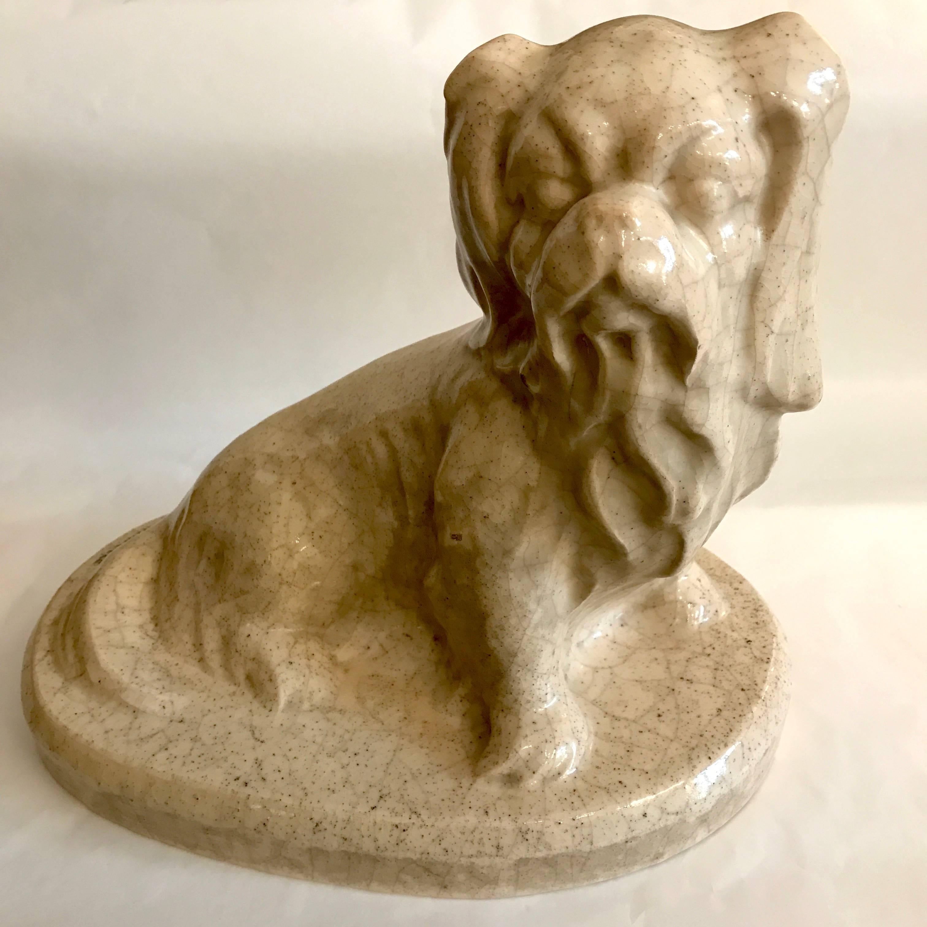 A Louis Fontinelle ceramic Art Deco Pekingese dog figure, in cream colored crackle glazed earthenware, depicting a Pekingese dog sitting on its hind legs, on a oval plinth, signed on the back L. FONTINELLE ; by the French artist (Paris