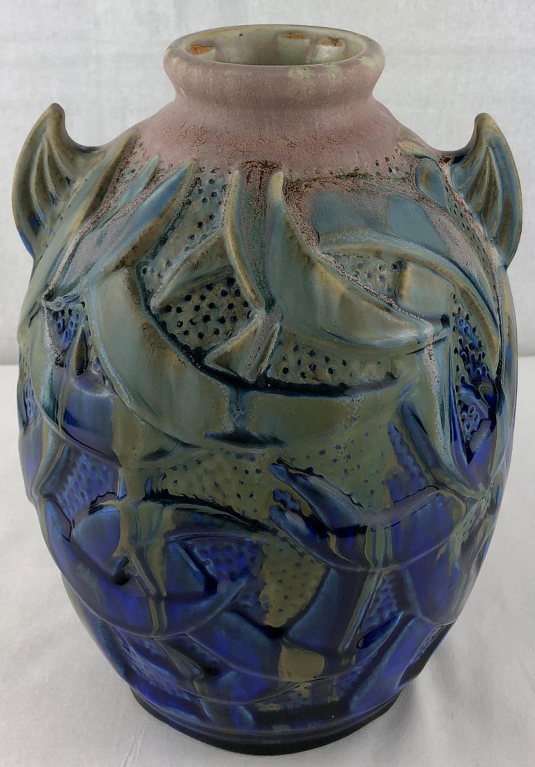 Beautiful French Art Deco vase with handles by Gilbert Méténier, signed.
This Art Deco period vase features two handles representing dolphin fins is made with flamed sandstone decorated with light pink, green drips on a blue background.

Gilbert