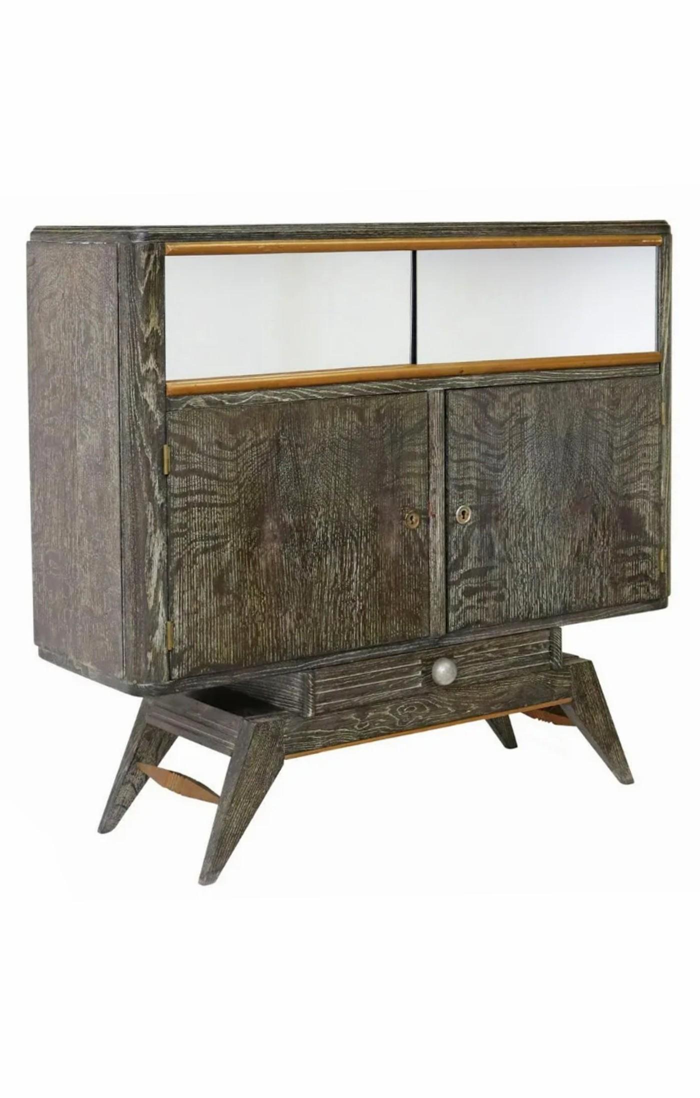 A fabulous French Art Deco period bar cabinet in highly sought-after cerused oak.

Hand-crafted in France in the early 20th century, high quality, most likely Parisian work, having sliding mirrored doors, over dual shelved cabinets, single lower