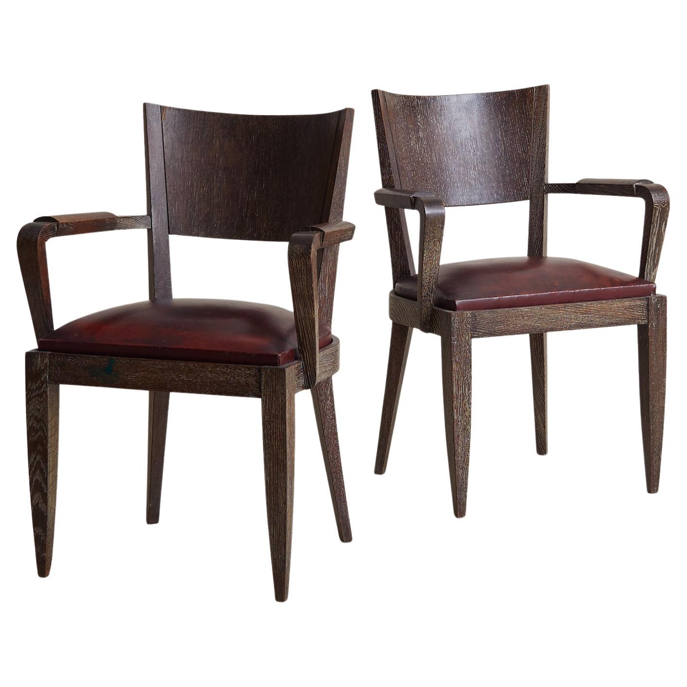 Se venden y cotizan individualmente.

Una silla fauteuil francesa de los años 40, definida por su silueta de influencia Art Déco. Las ricas vetas texturadas del roble cerusado resaltan el marco anguloso, mientras que los reposabrazos esculpidos