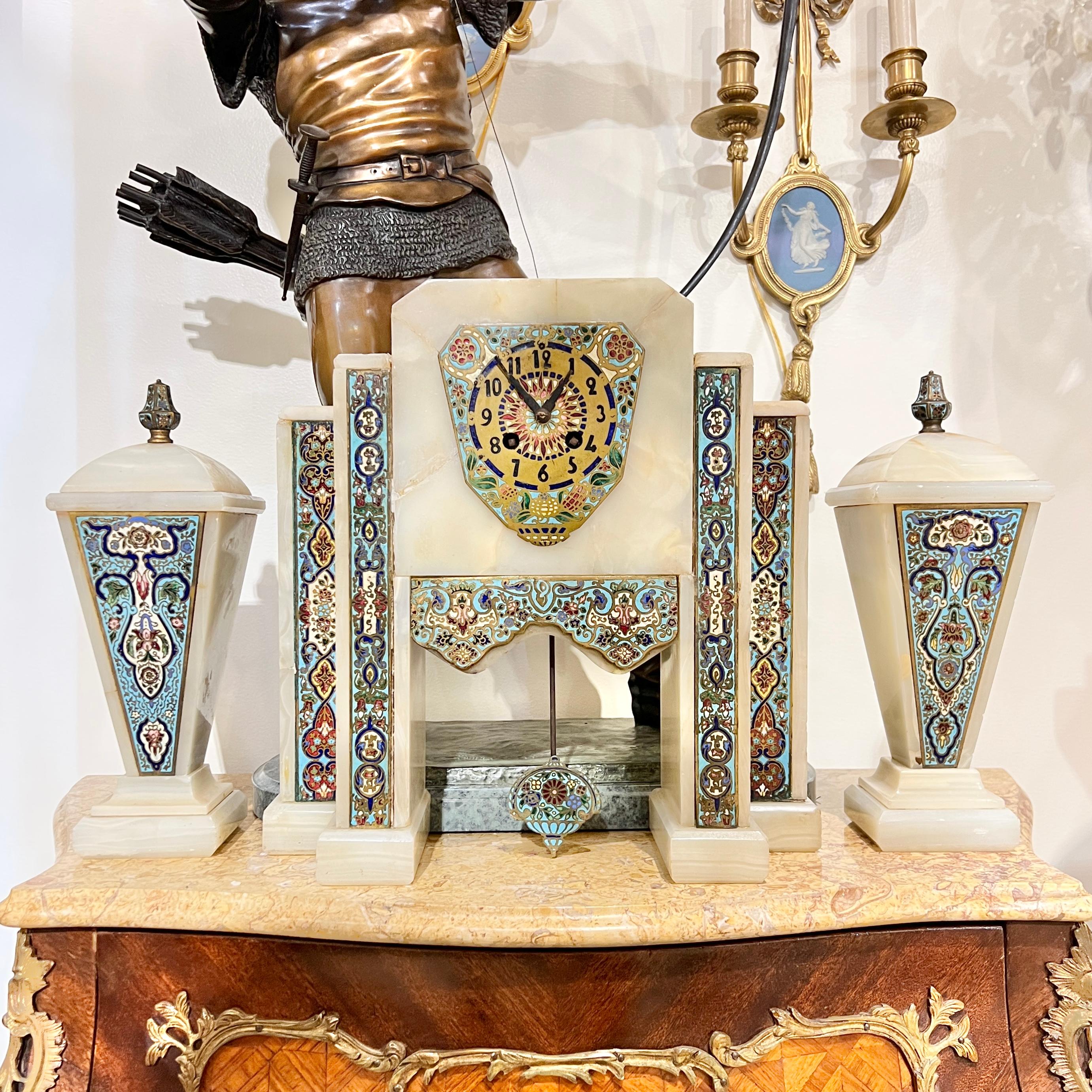 French Art Deco period mantel clock and obelisks garniture (set), circa 1920s, crafted from onyx stone with champleve enameled bronze mounts.  Clock 14 1/4 inches tall and the obelisks 12 1/4 inches tall.
