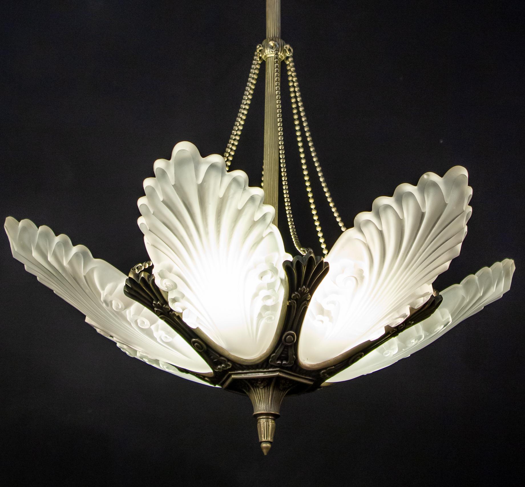 Elegant French Art Deco chandelier with six grand clear frosted molded shades with a silvered metal frame. 
We can Rewire to U.S. standards which accommodate six E 14 light bulbs .
Custom drop; we can shorten the rod on request.